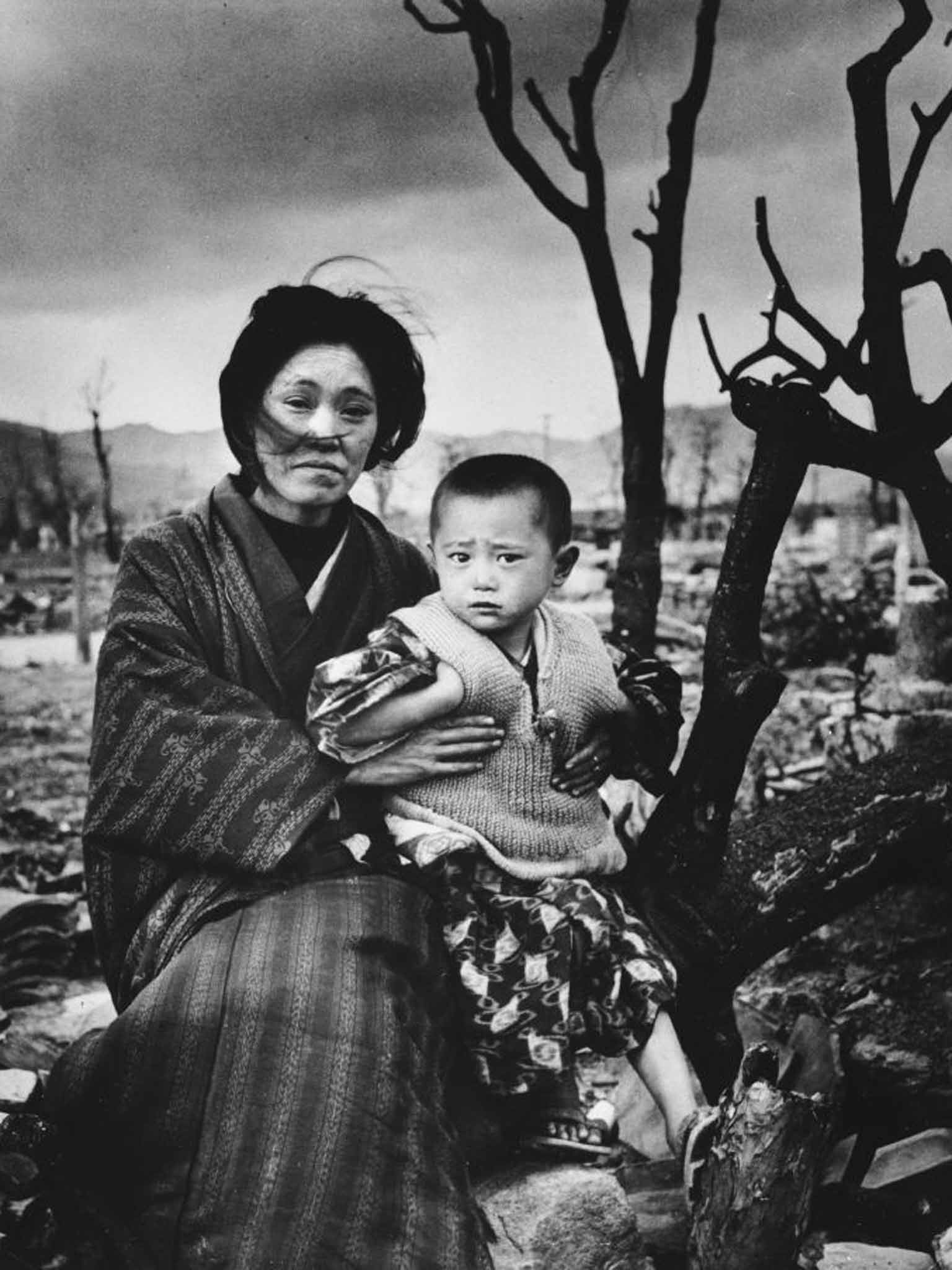 A mother and child sit in the debris of Hiroshima