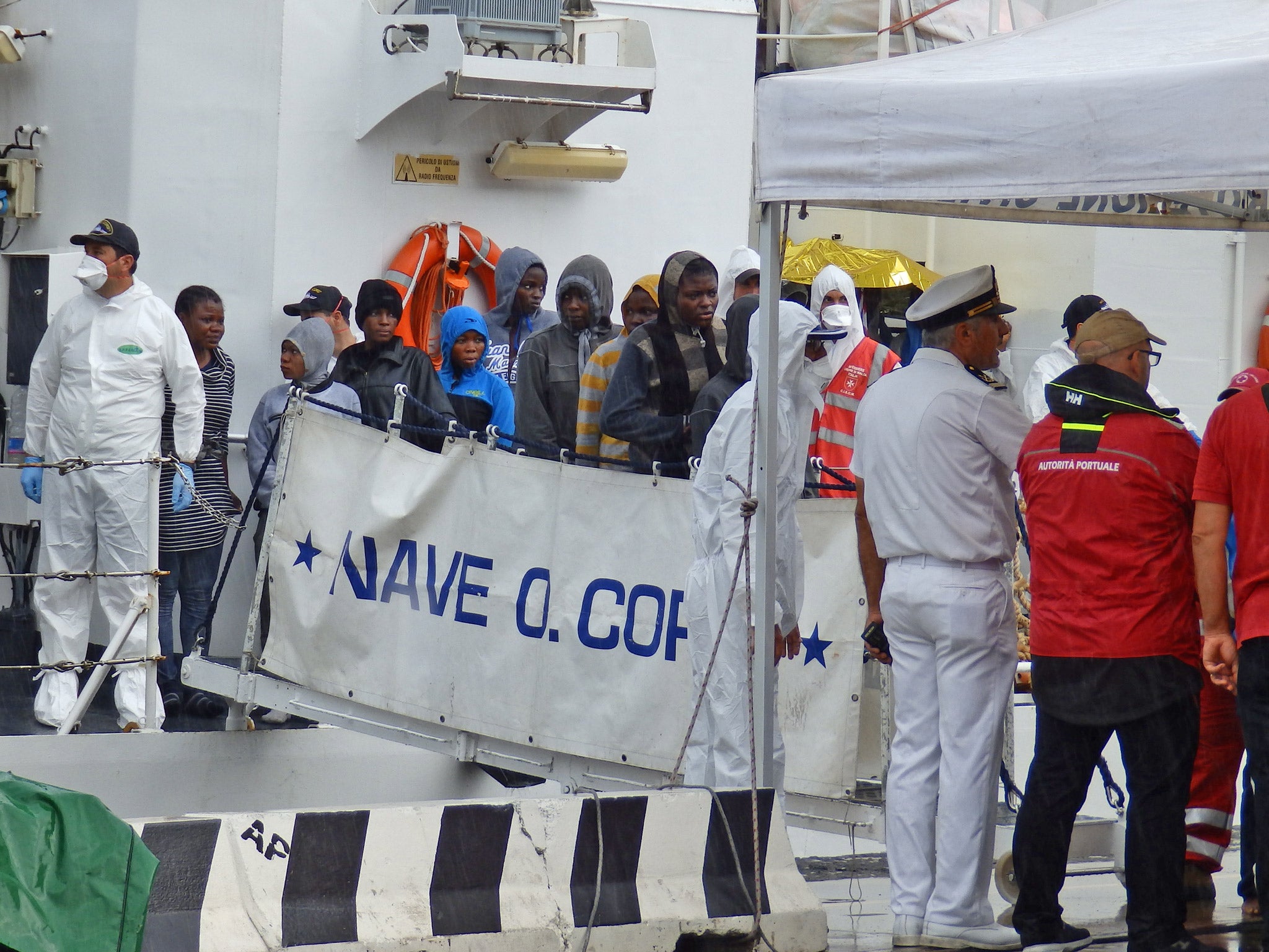 Migrants disembarking from an Italian coastguard ship in Messina