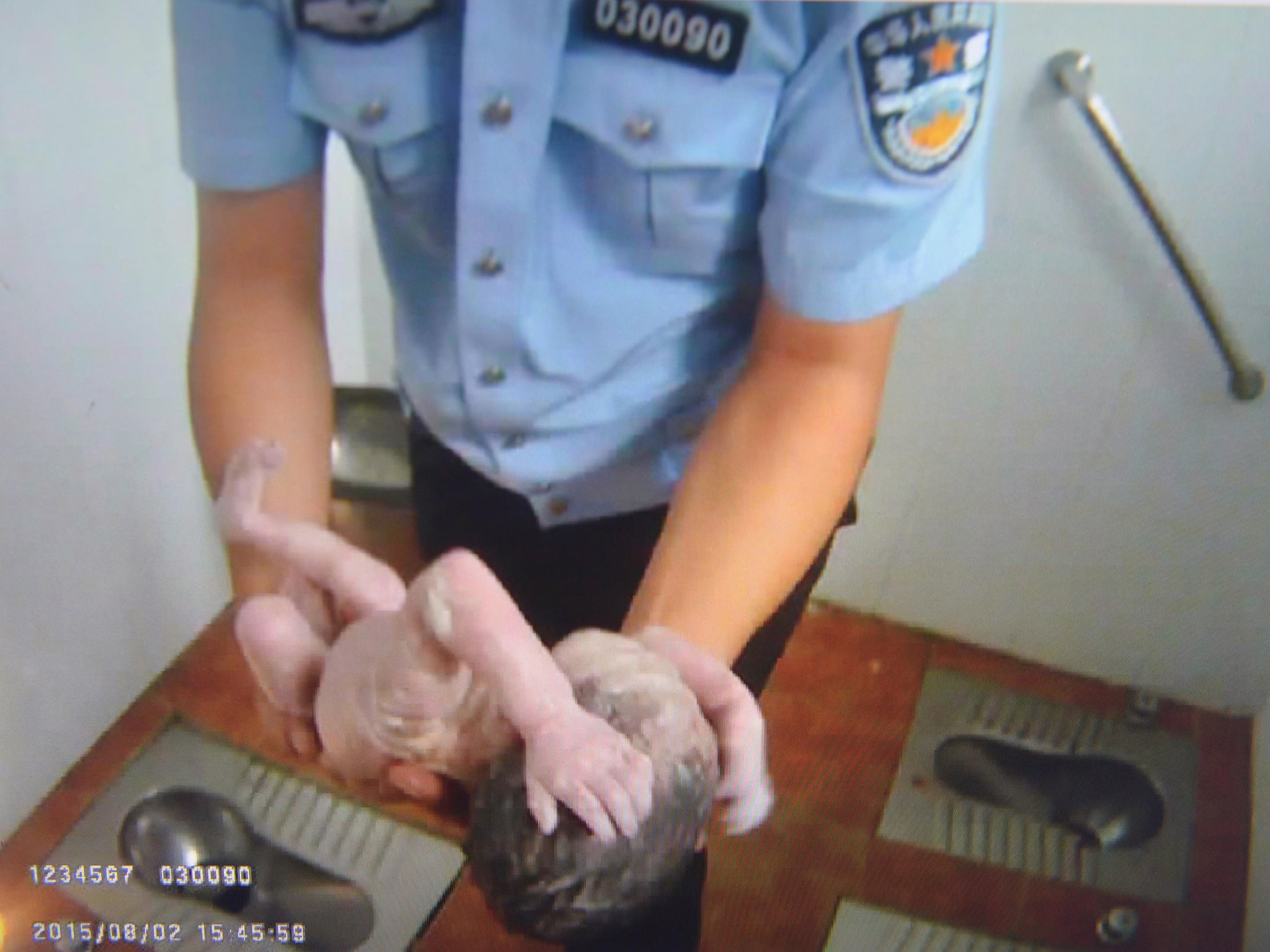 A policeman holding an abandoned newborn baby in a public toilet in Beijing