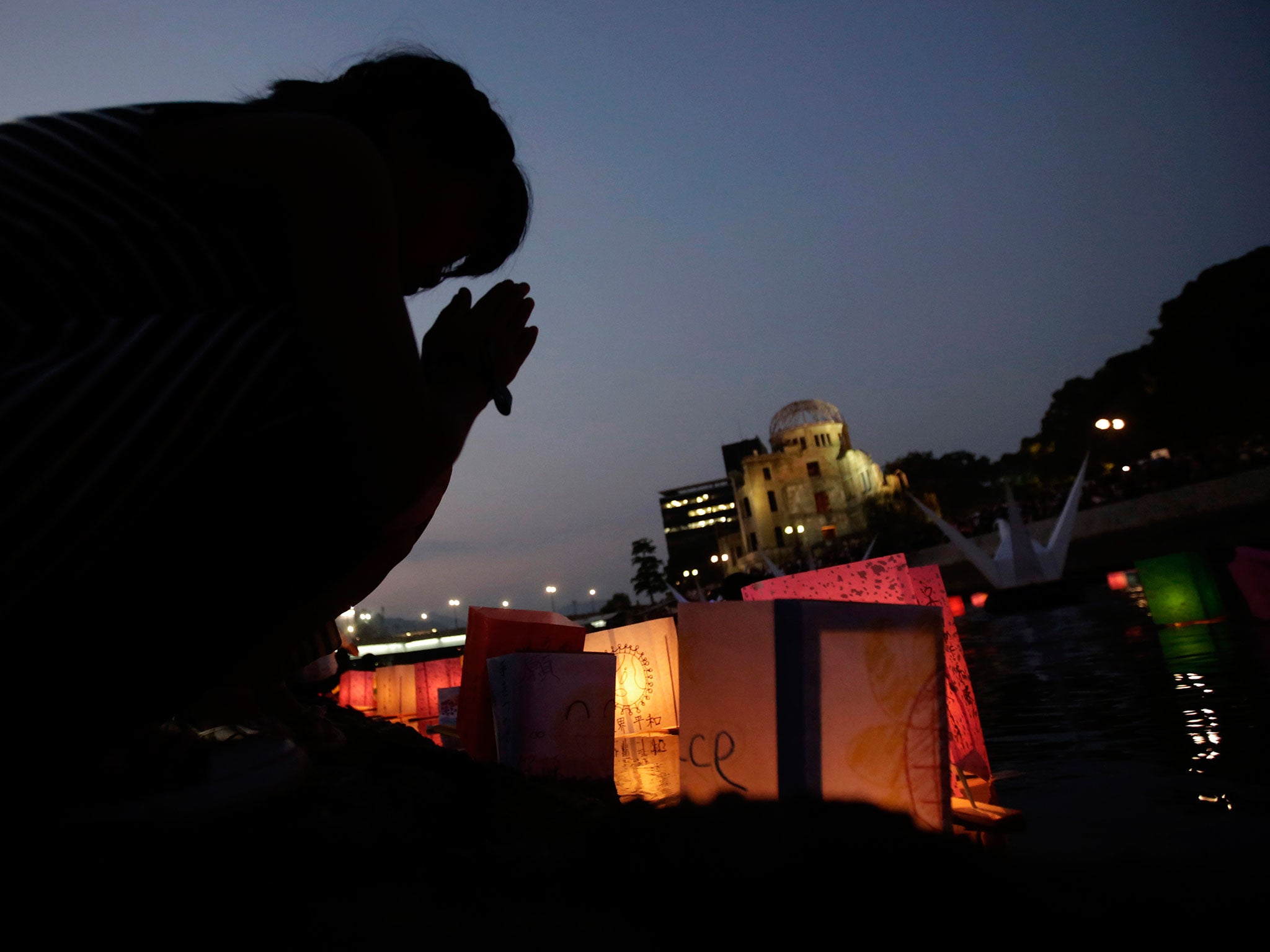 A woman offers prayers as she releases paper lanterns with other citizens to the Motoyasu River