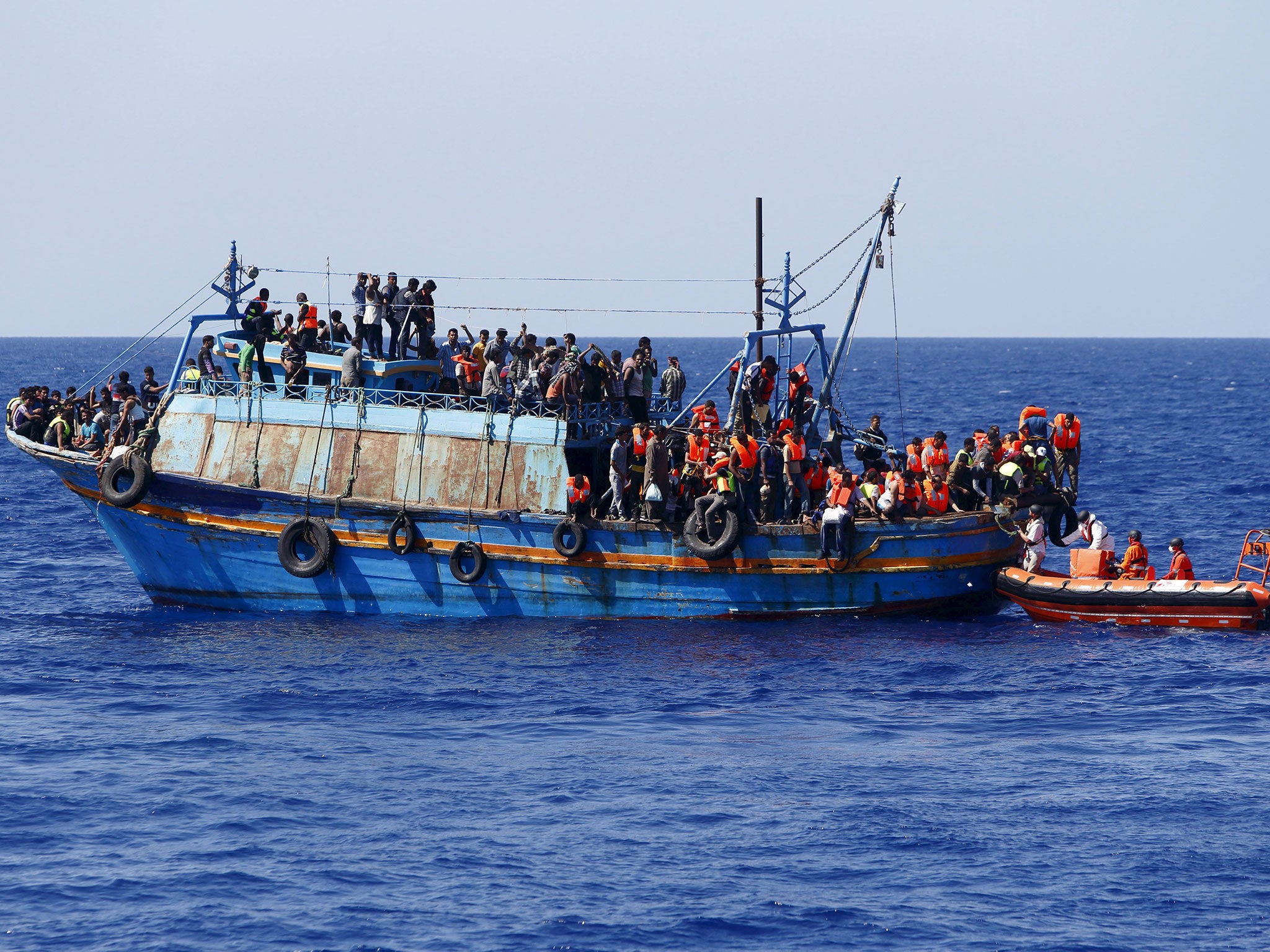 Migrants on board an overloaded wooden boat are rescued some 10.5 miles (16 km) off the coast of Libya August 6, 2015.