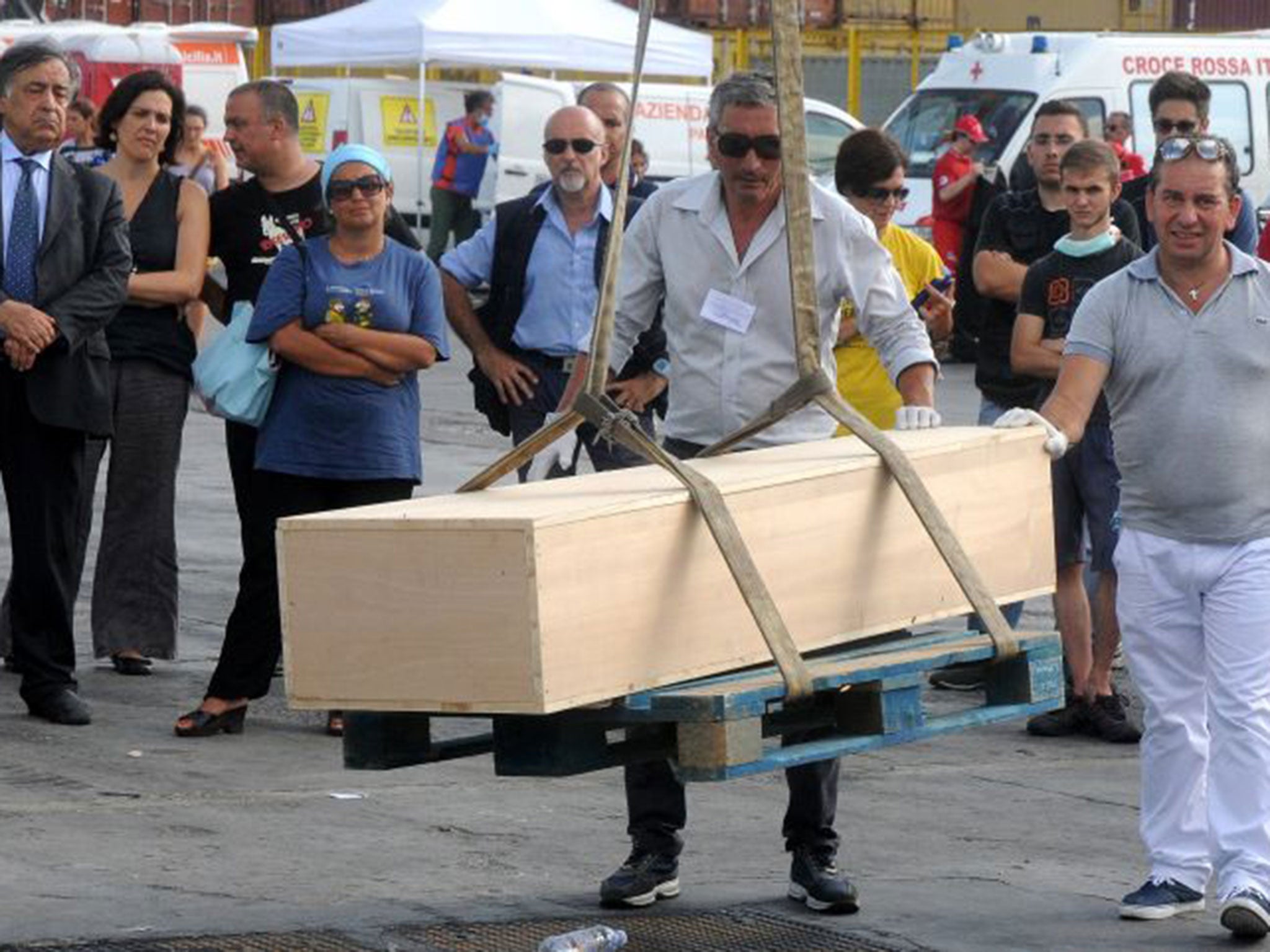 Palermo's Mayor Leoluca Orlando, left, looks at the a coffin with the body of a migrant oaded off the Doctors Without Borders ship ìBourbon Argosî