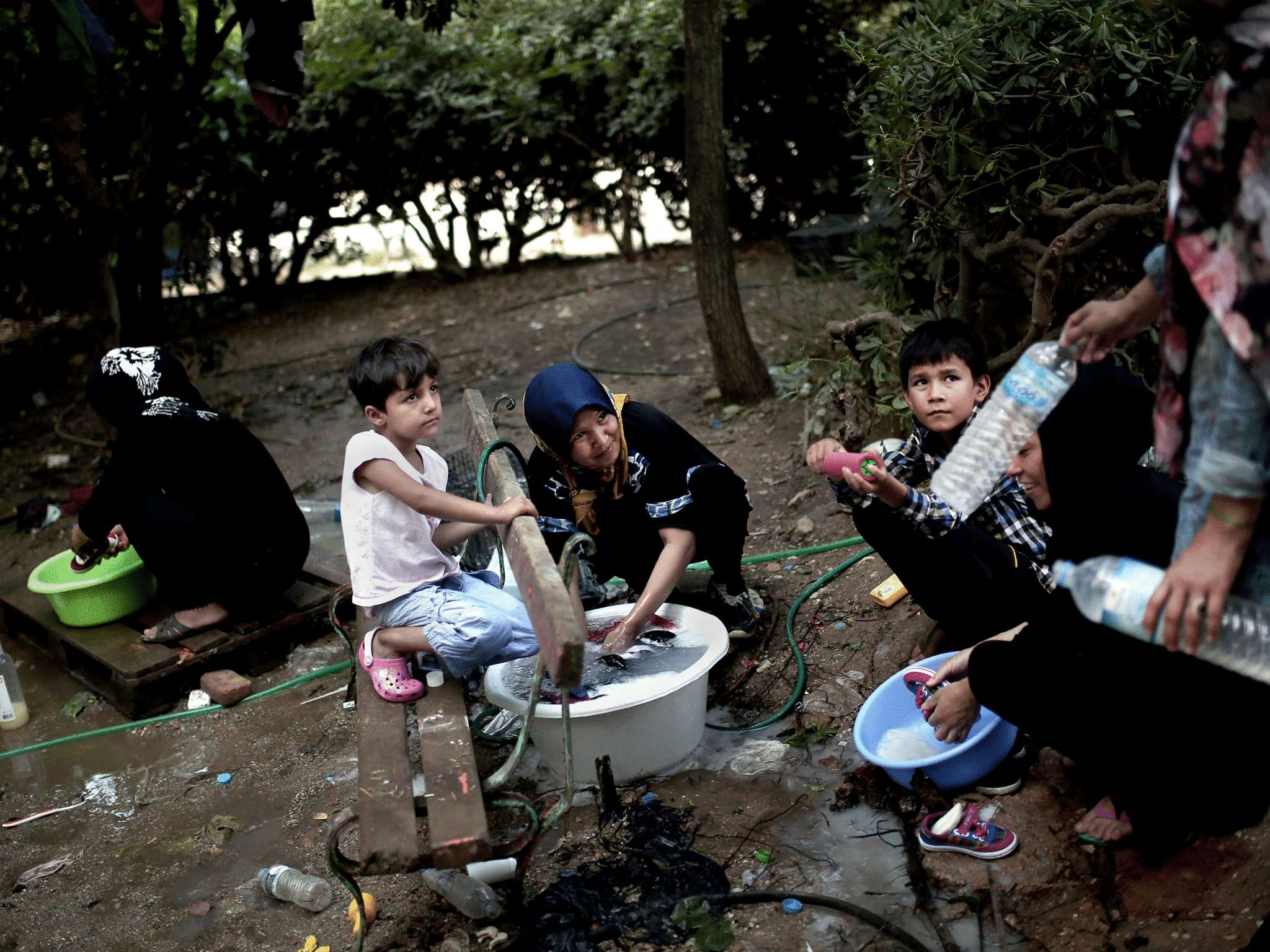 Migrants wash their clothes in a park in central Athens