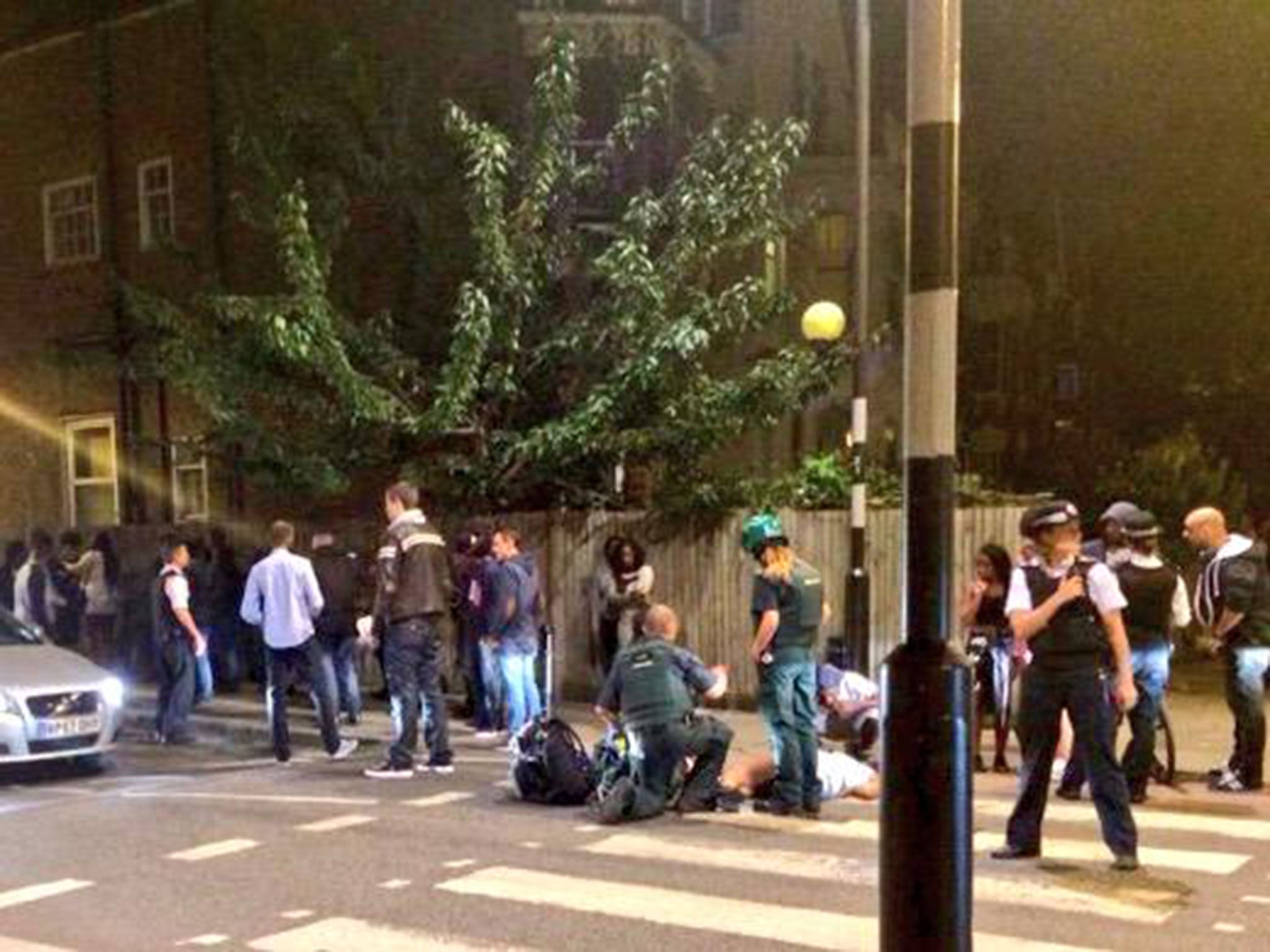 Police stand guard as paramedics treat a person at the scene in Stamford Hill, where officers were attacked by more than 400 people