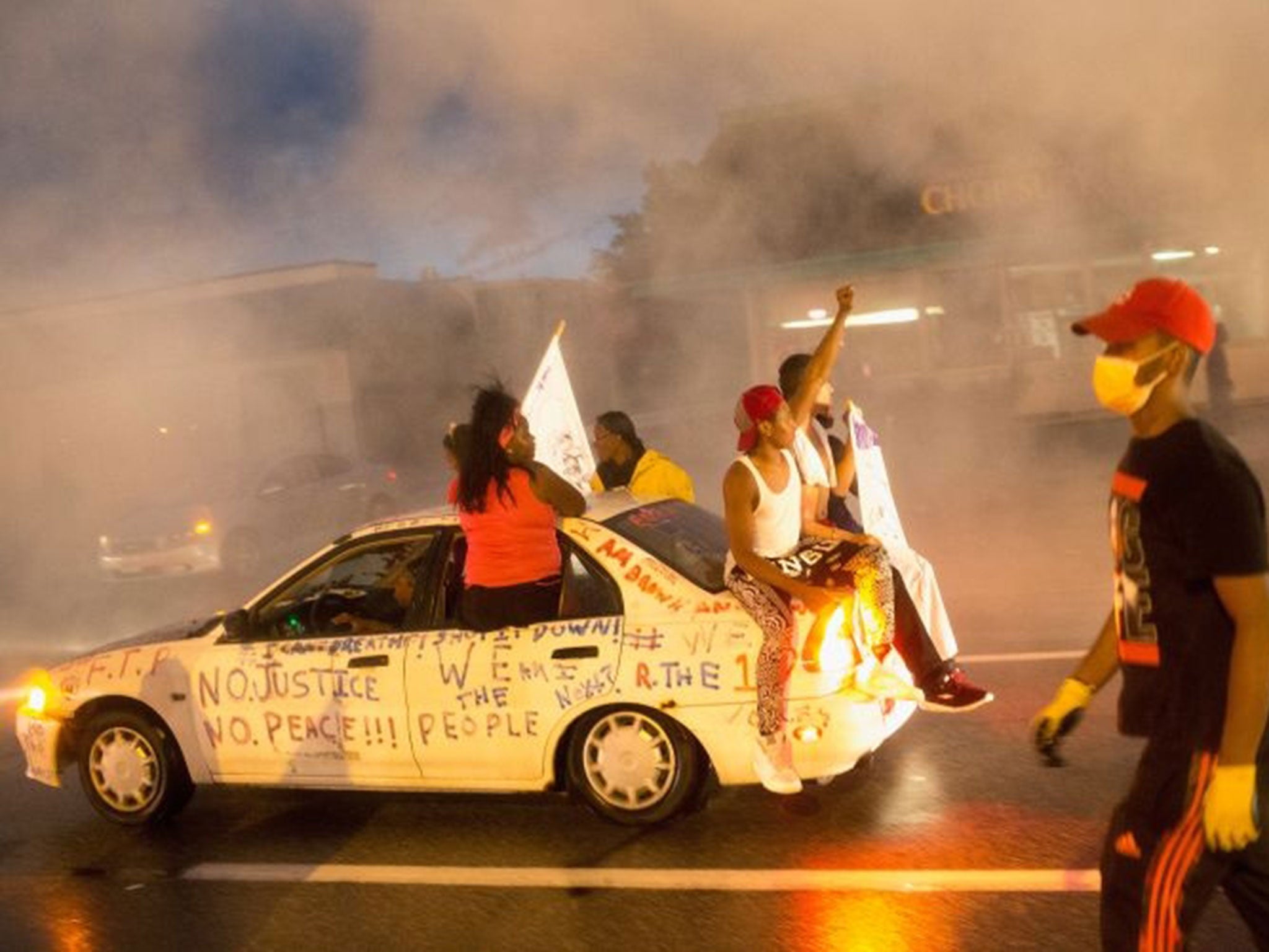 Protesters sit atop a car emblazoned with slogans calling for justice