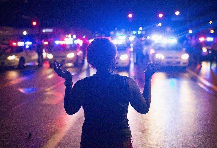 A demonstrator faces a line of police cars (Image: Scott Olson/Getty Images)