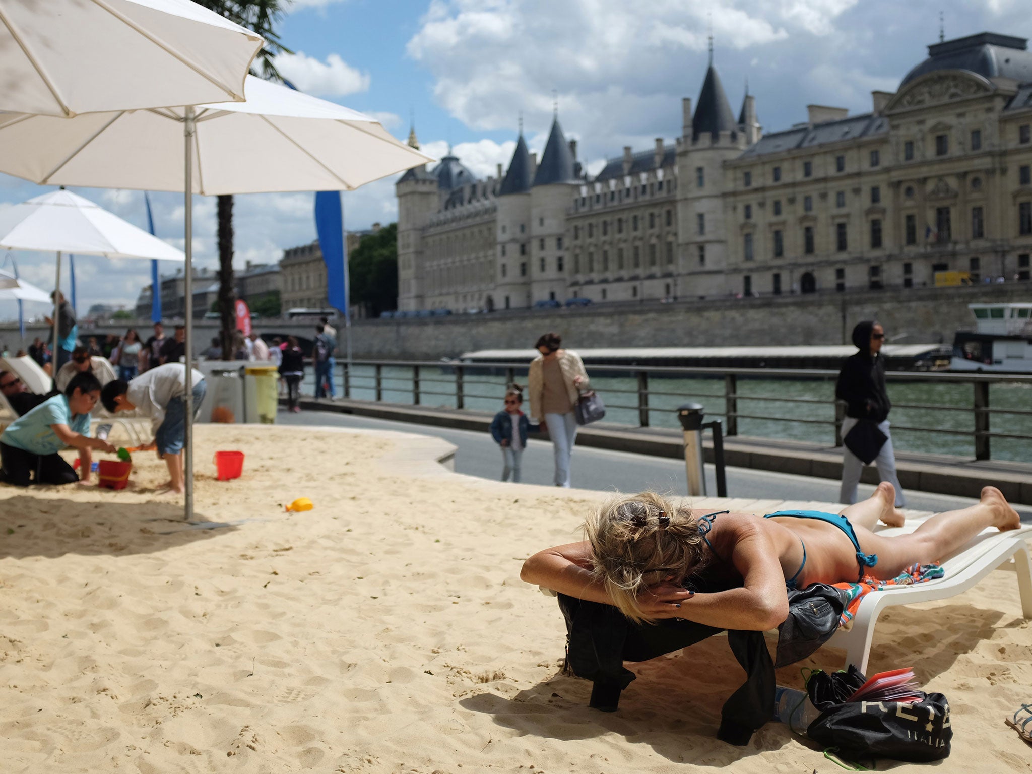 People relax on the sand during the 'Paris Plage' (Paris Beach) event on the banks of the river Seine in Paris