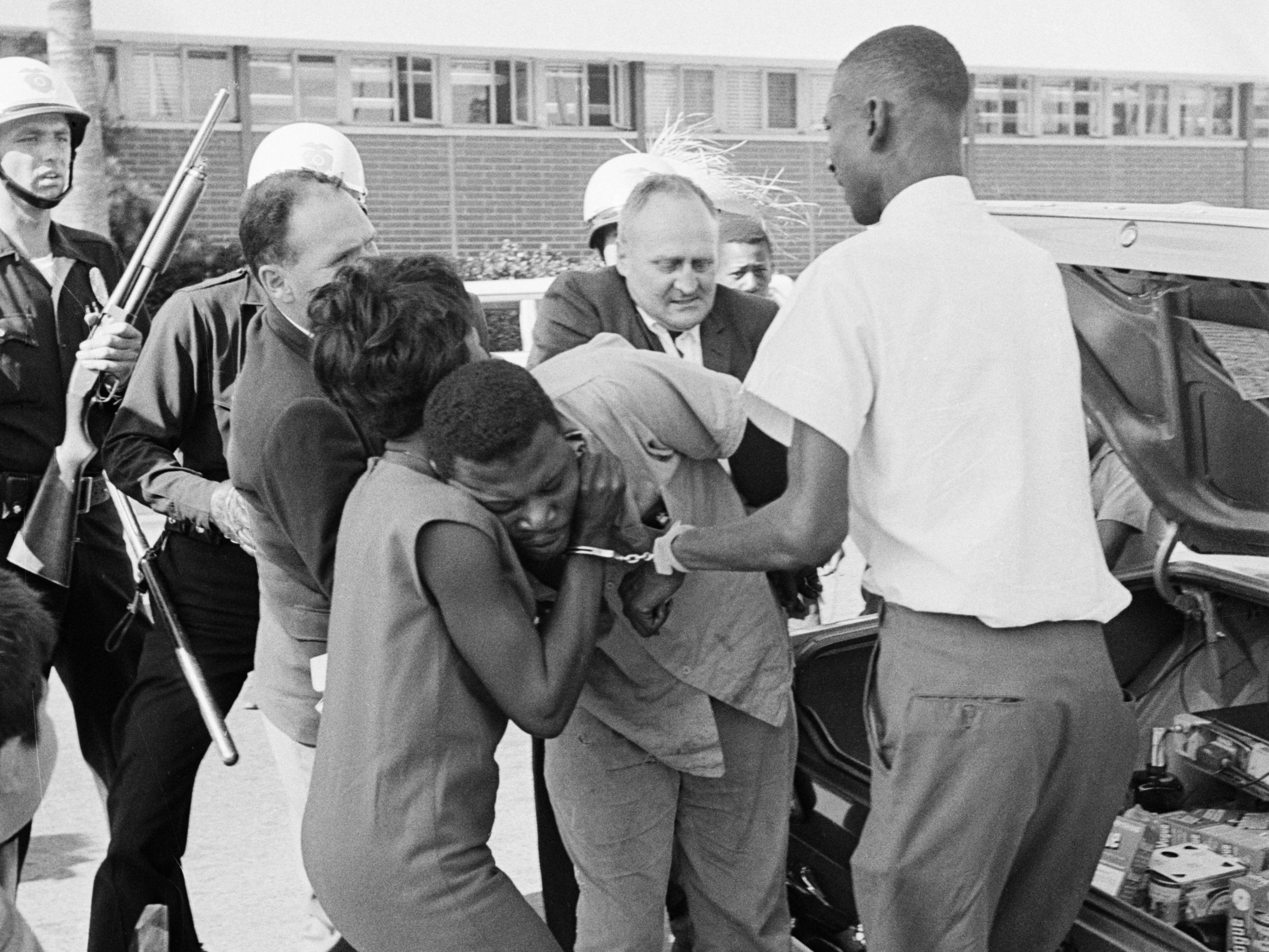 Police grapple with riot suspects outside the Los Angeles police station as they are being transferred to central headquarters. The violence began on 11th August 1965, 50 years ago today, after a black motorist was arrested for drunk driving and a minor r