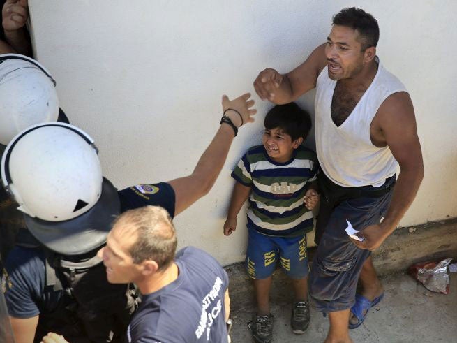 A child cries as his father argues with a riot police officer during a registration procedure at the national stadium of the Greek island of Kos, August 12, 2015.