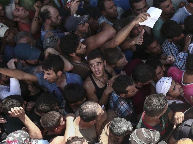 Migrants queue for registration inside a stadium in Kos