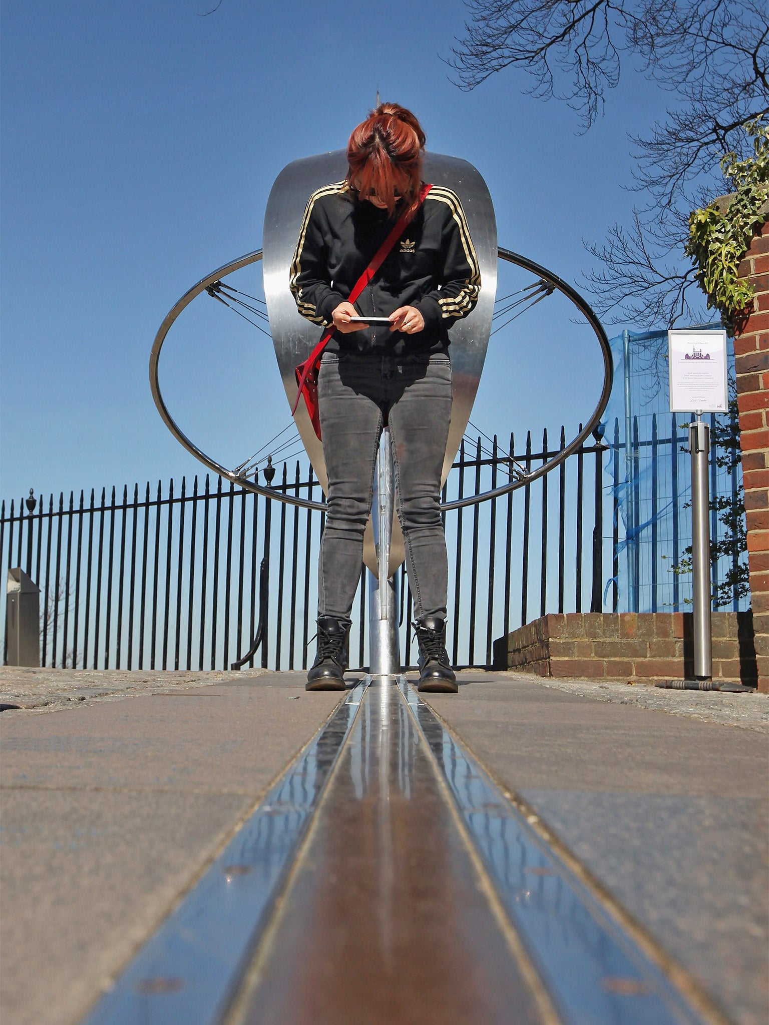 A tourist stands astride at the 'Prime Meridian of the World' (Getty)