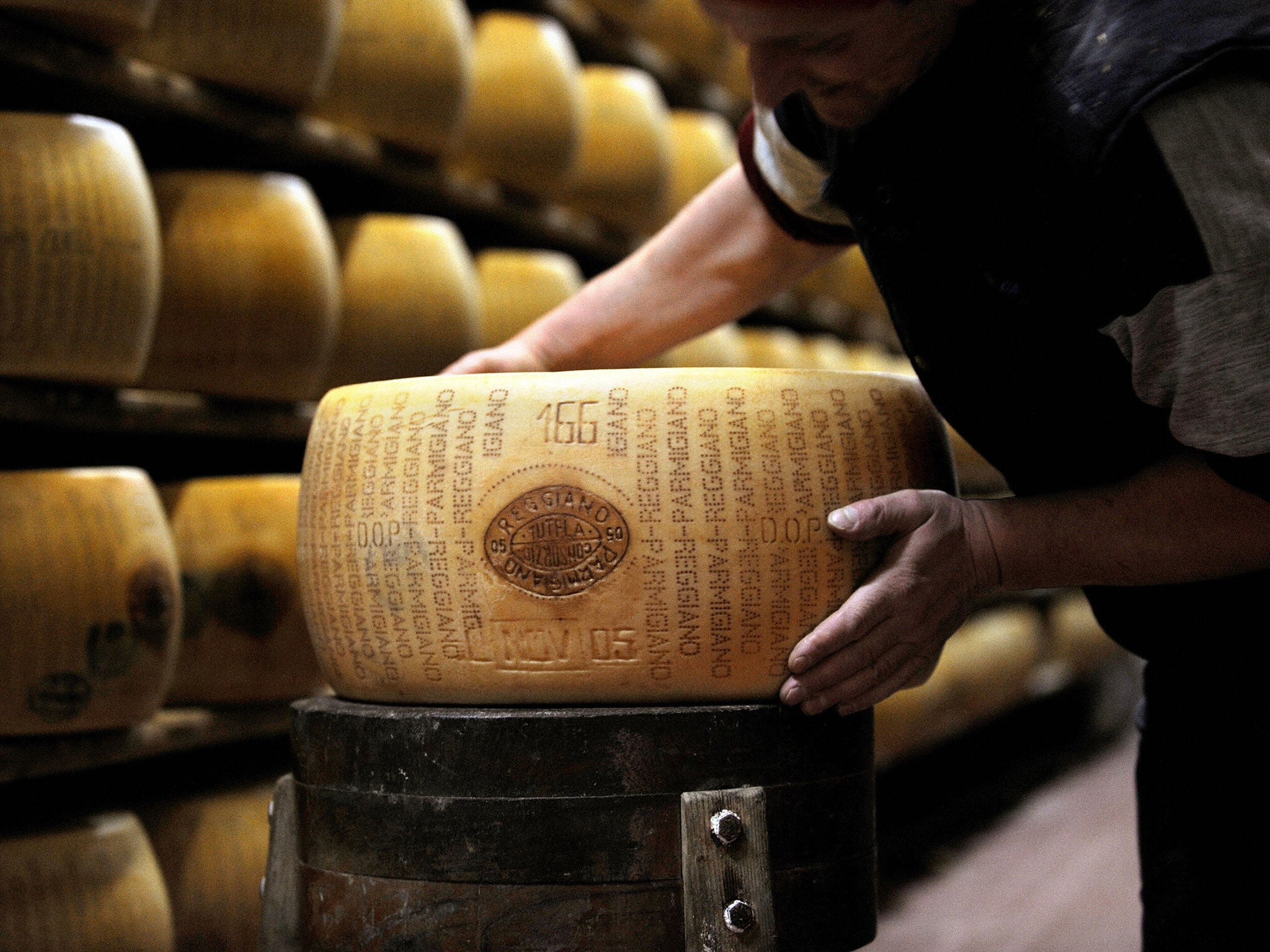 A picture taken on February 15, 2008 shows a worker checking a wheel of seasoned Parmigiano Reggiano cheese in a factory in Valestra, near Reggio Emilia