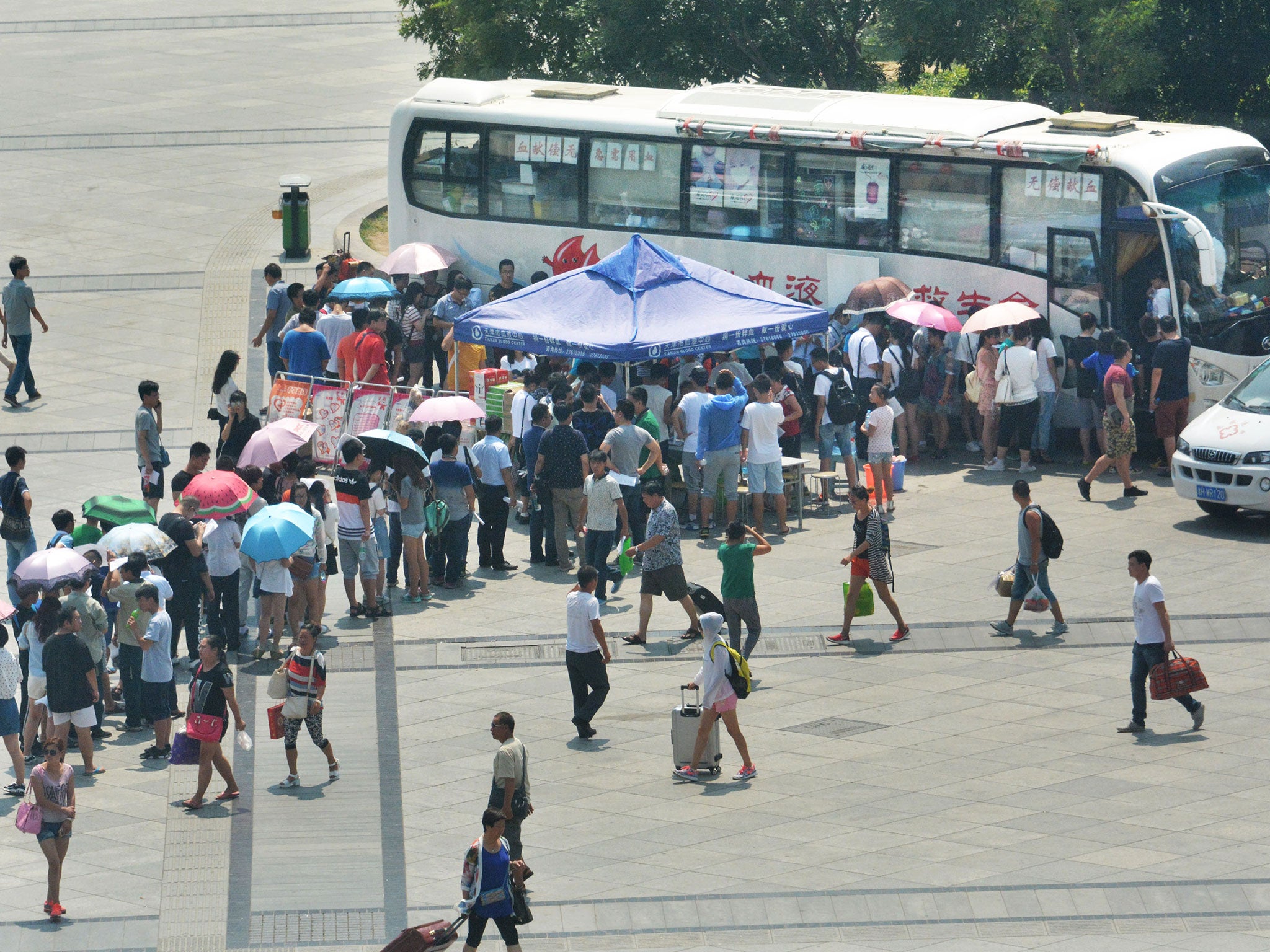 People queue to give blood outside a donation bus at Tianjin Railway Station in Tianjin, north China