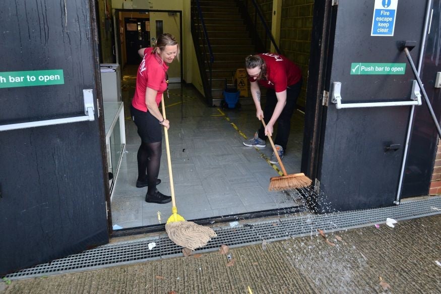 Staff mop flood water out of the Arndale Centre in Eastbourne, on the south coast (PA)