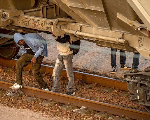 Migrants hide under a freight car in Coquelles near Calais pm on their way to the Eurotunnel on 12th August