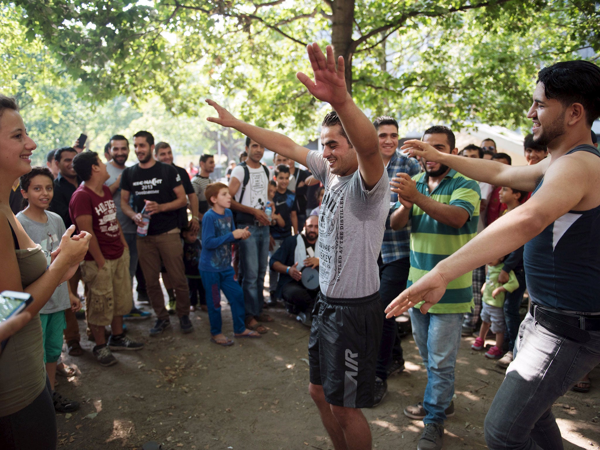 Volunteers play music with migrants and dance in front of the Berlin State Office for Health and Social Affairs where they wait with other migrants to apply for asylum in Berlin, August 10, 2015