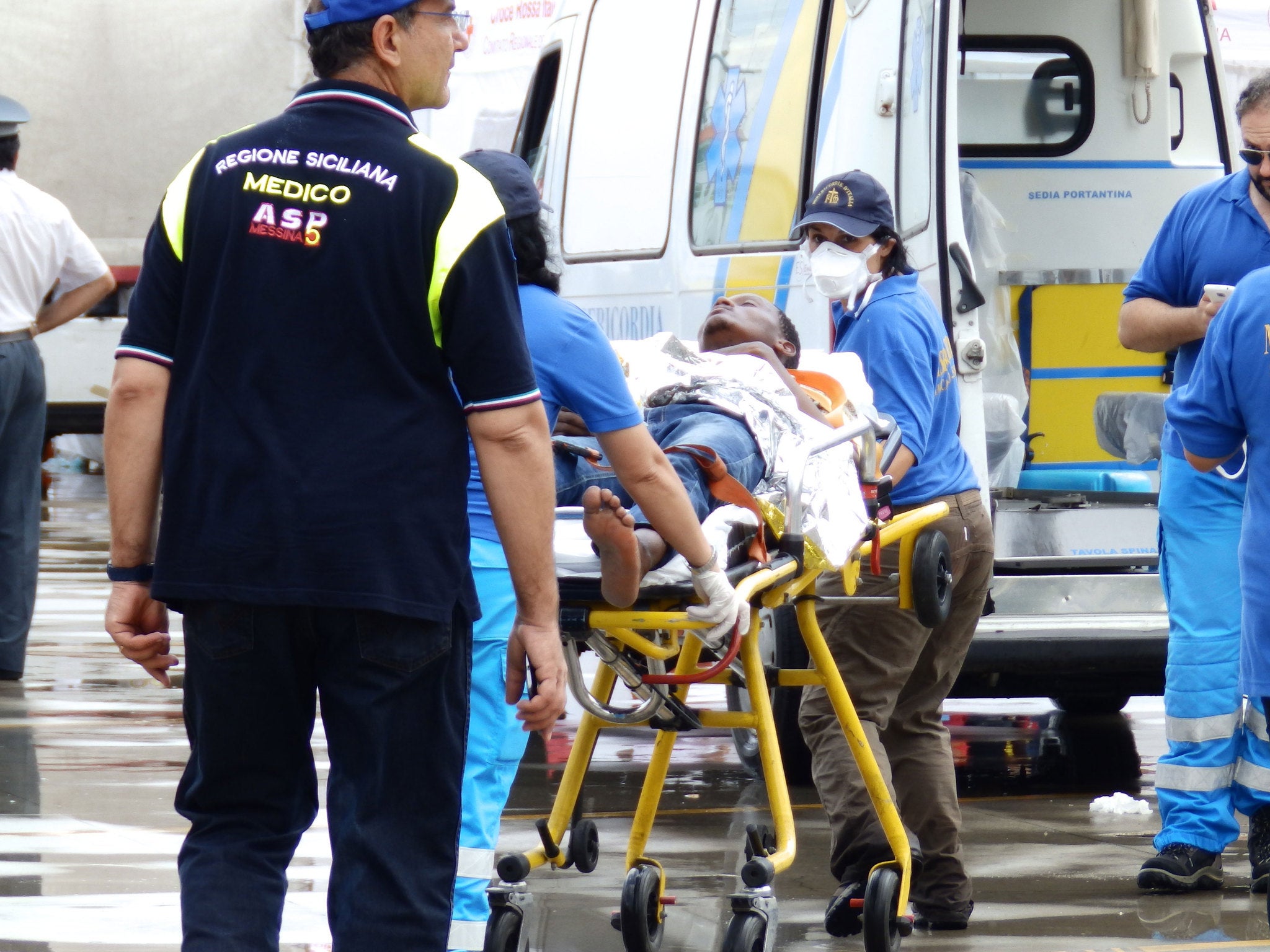 An injured migrant being put in an ambulance after landing on a rescue boat in Messina, Sicily, on 4 August