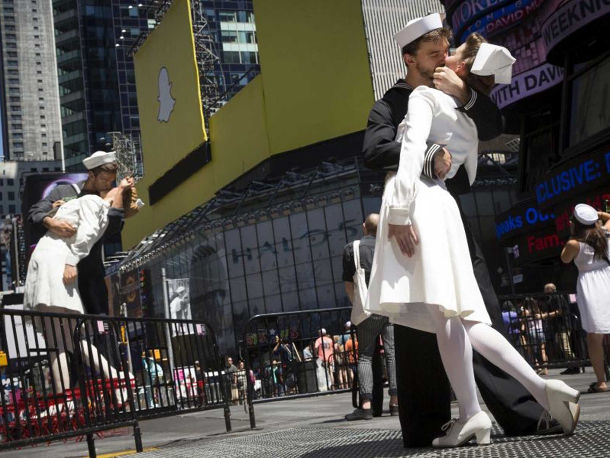 A couple kiss in front of the sculpture