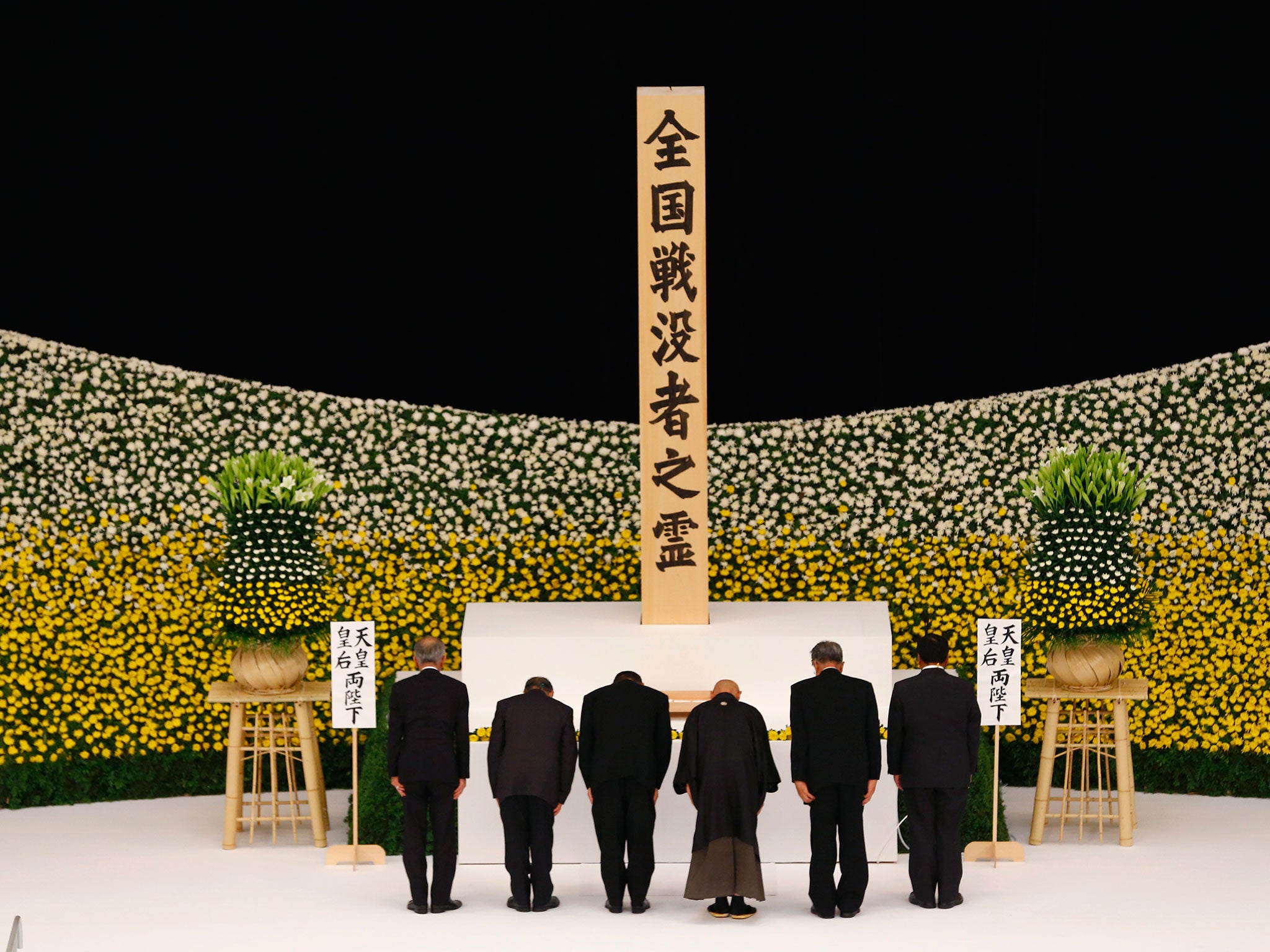 Relatives of the war dead add flowers to a bank of chrysanthemums in the Budokan Hall, Tokyo