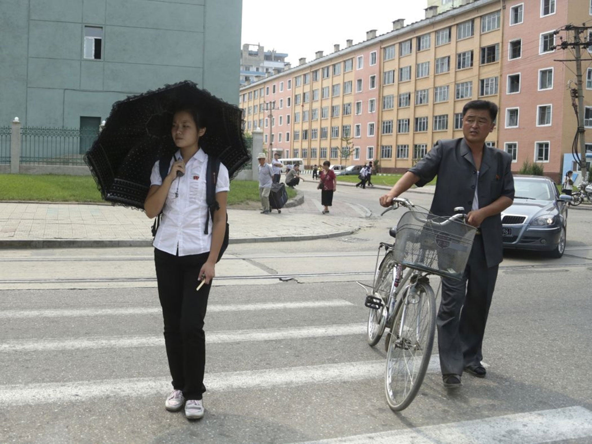 North Koreans pause to give way for passing vehicles as they cross a road in Pyongyang, North Korea, Sunday, Aug. 16, 2015. North Korea celebrated the 70th anniversary of the liberation of the Koreas from the Japanese colonial rule on Aug. 15.