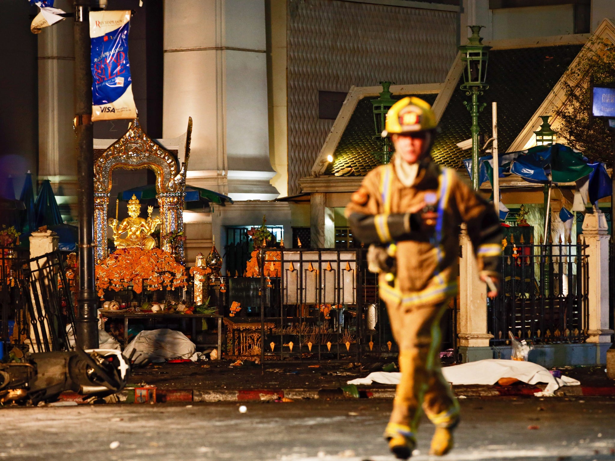 body lies covered on the ground as a firefighter runs on the foreground at the scene -