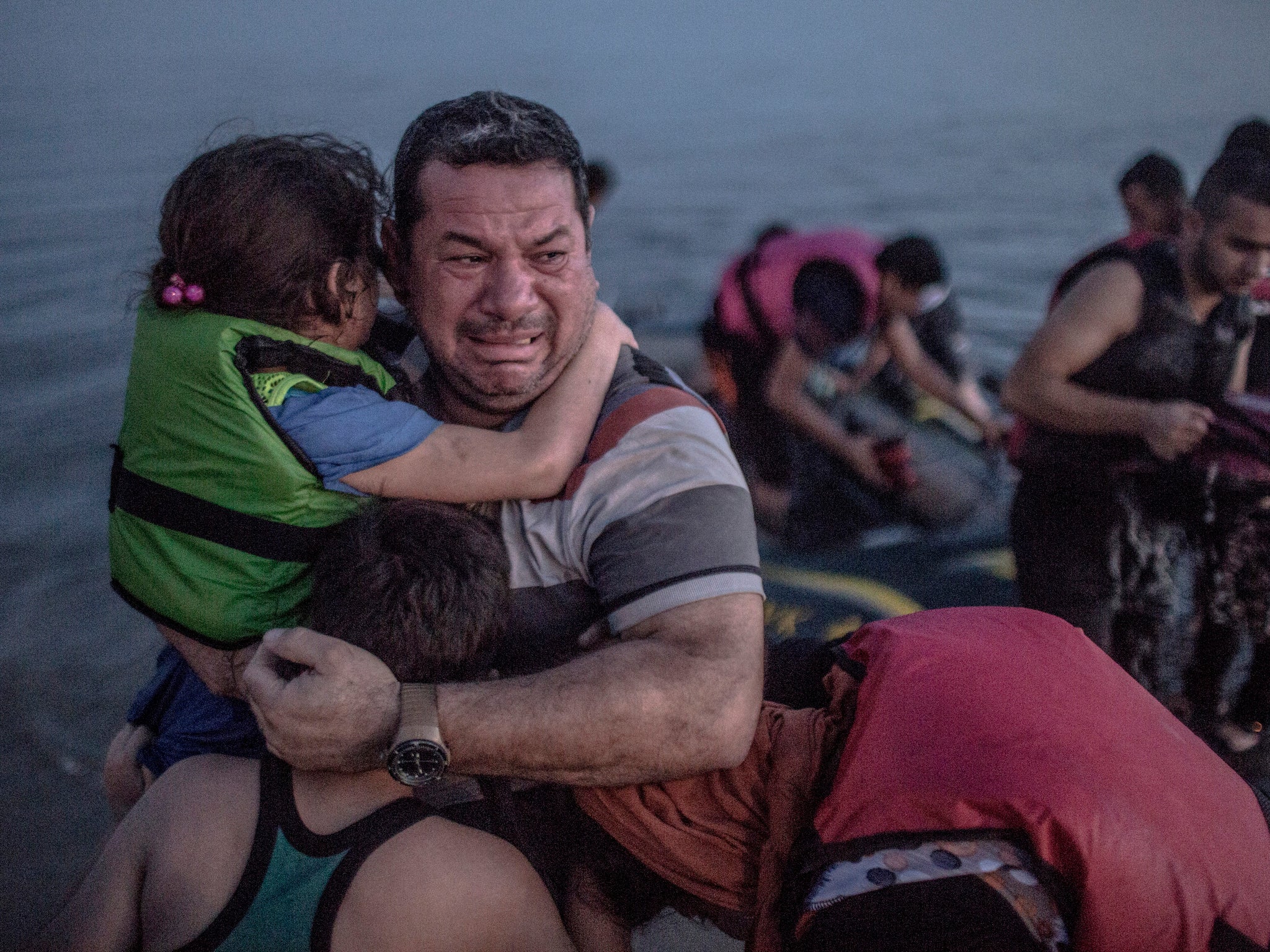 A Syrian father holds his children close as his arrives on the Greek Island of Kos