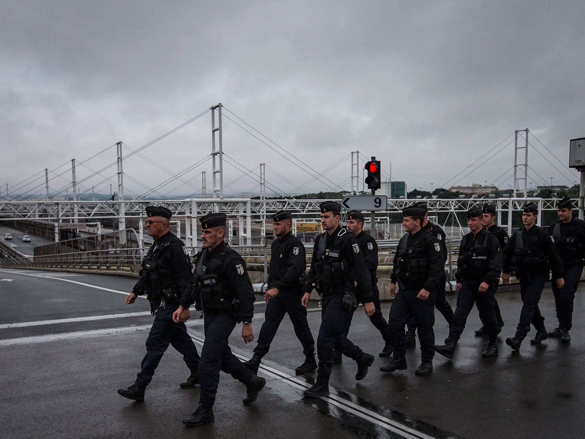 French police officers walk on an overpass above the boarding platforms for Eurotunnel trains, neat the tunnel entrance in Calais