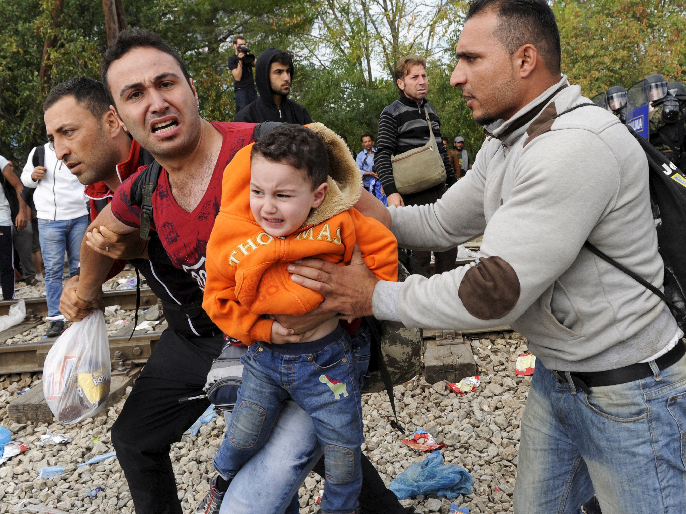 A migrant reacts as he carries a child during clashes with Macedonian police