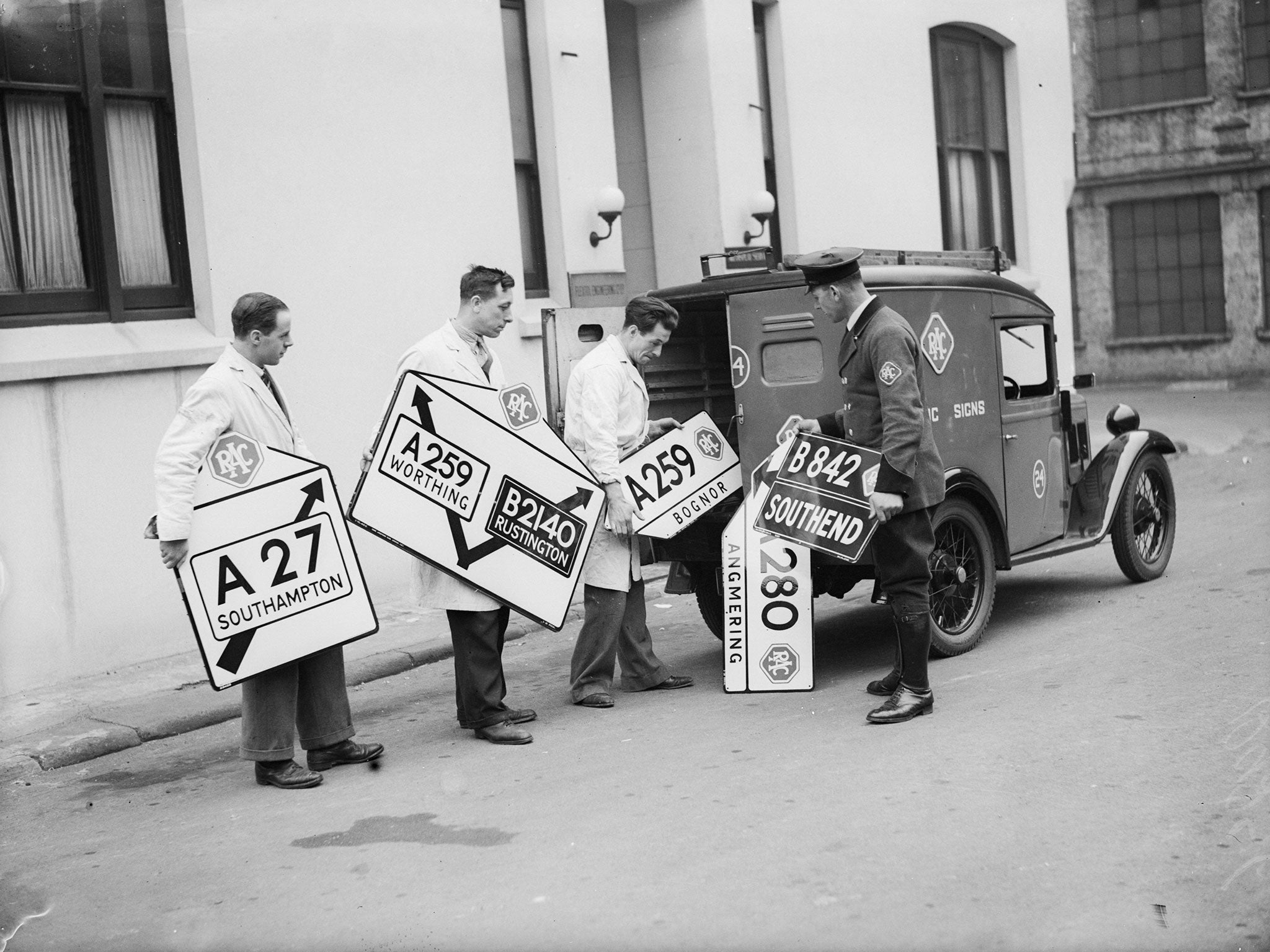 8th April 1936: New roadsigns being loaded into a van at the RAC sign factory at Victoria, London.