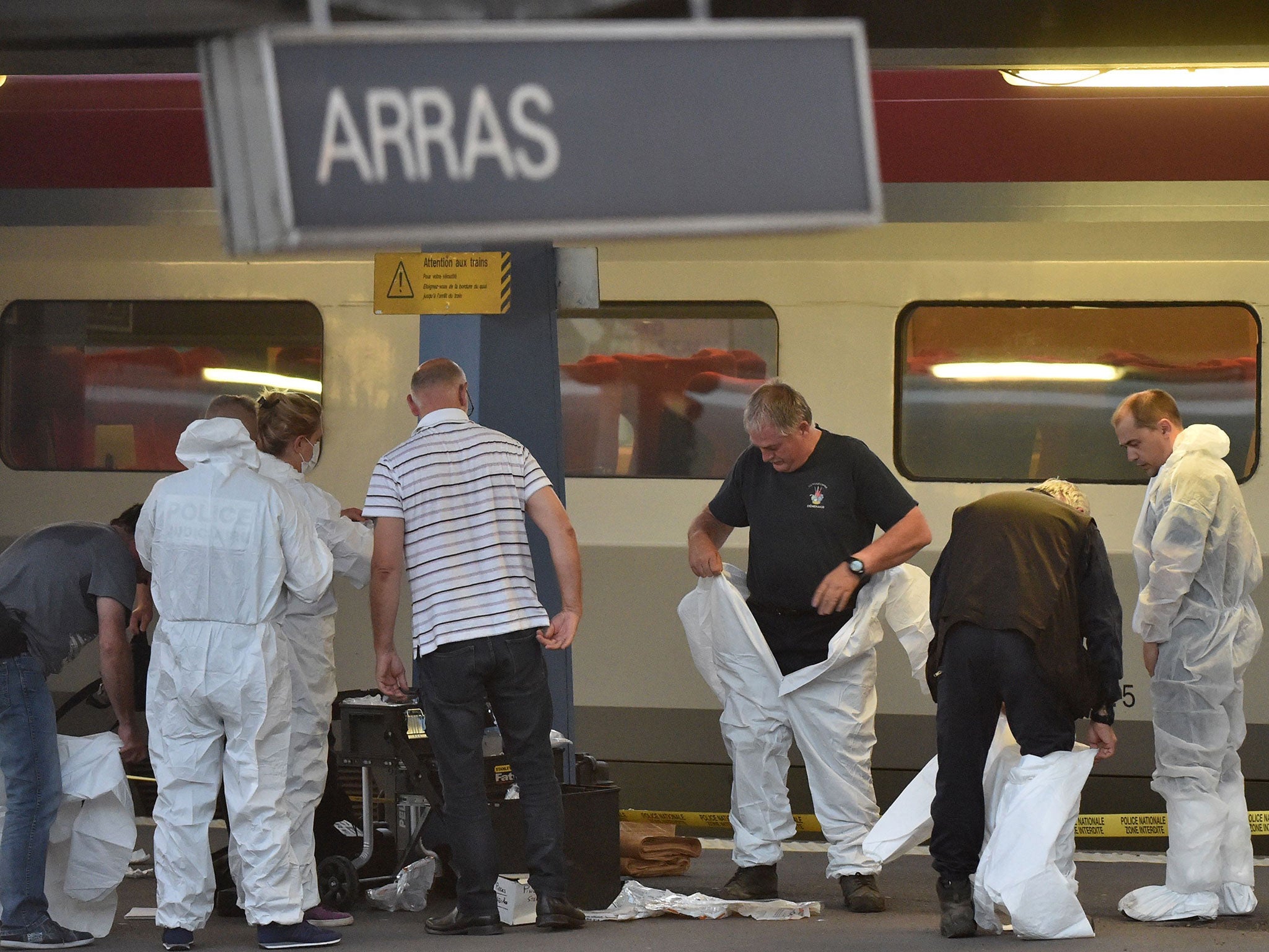 Criminal and forensic investigators put on protective suits on a platform next to a Thalys train of French national railway operator SNCF at the main train station in Arras, northern France, on August 21, 2015