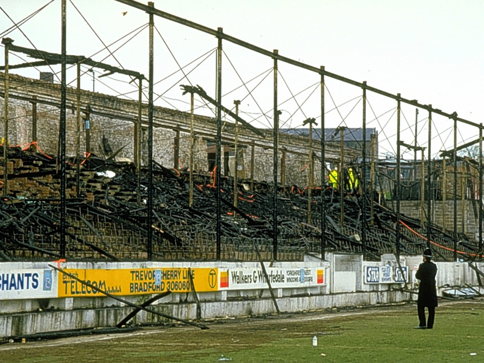 A policeman stands in front of the burnt out stand after the Bradford City disaster