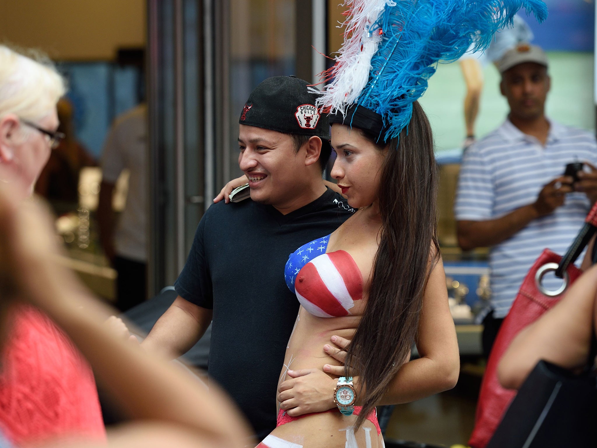 A young woman poses with tourists in Times Square wearing body paint to cover herself August 19, 2015 in New York