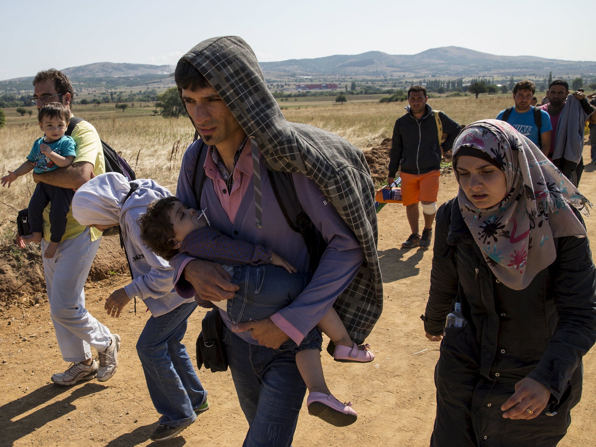 Migrants from Syria walk along a road in the village of Miratovac near the town of Presevo, Serbia