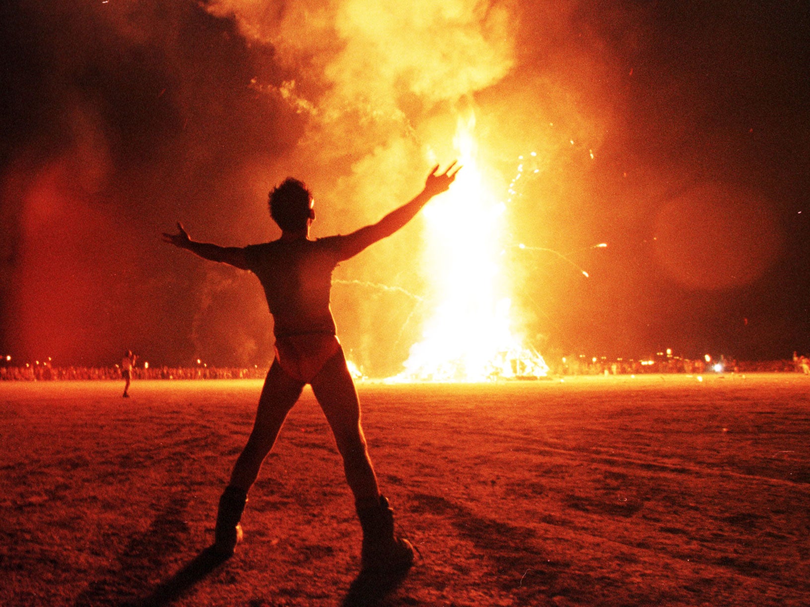 A 'Burner' watches as the Burning Man festival culminates with the burning of a giant wooden effigy