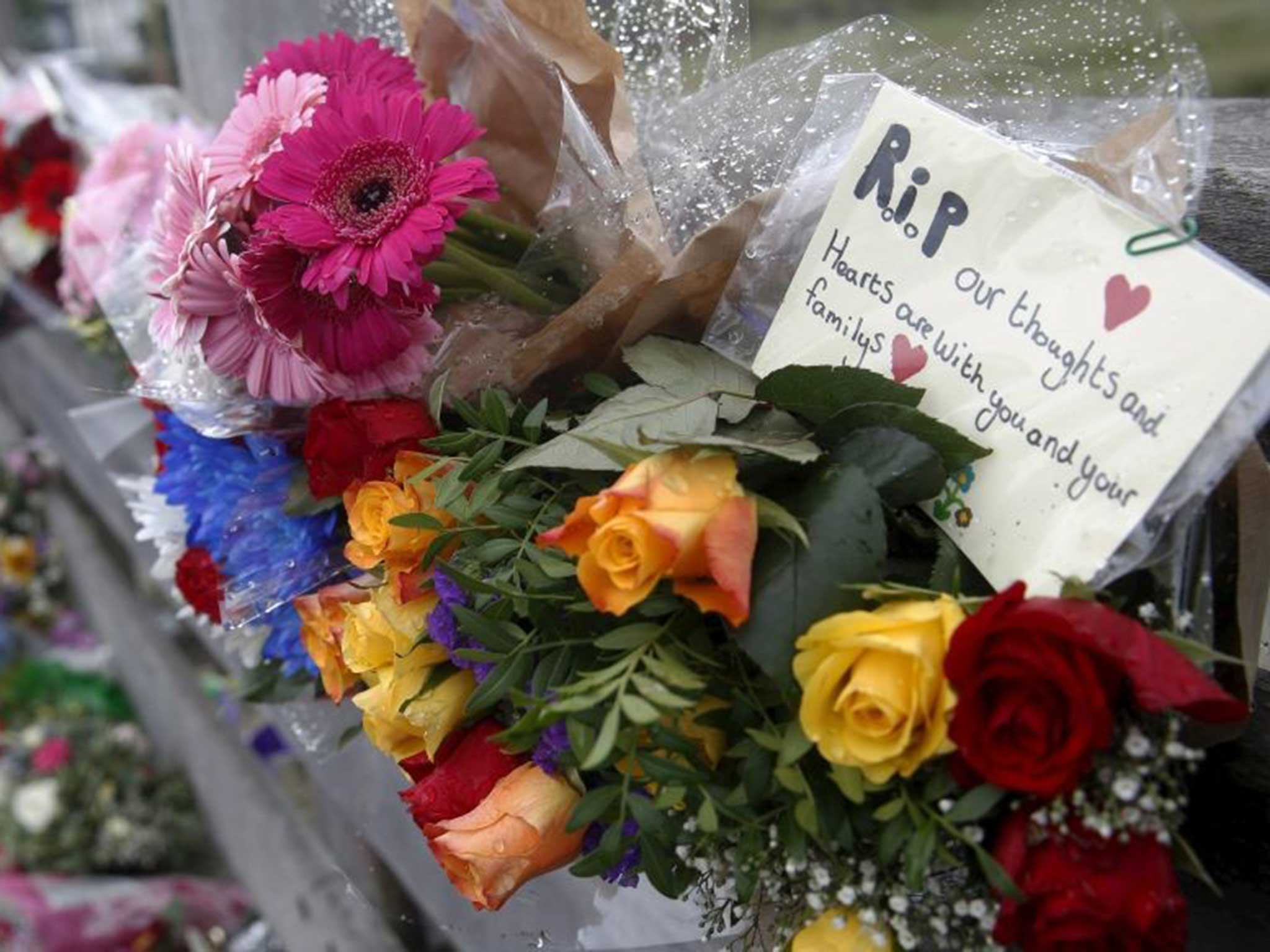 People leave flowers for the victims near the scene where the Hawker Hunter came down