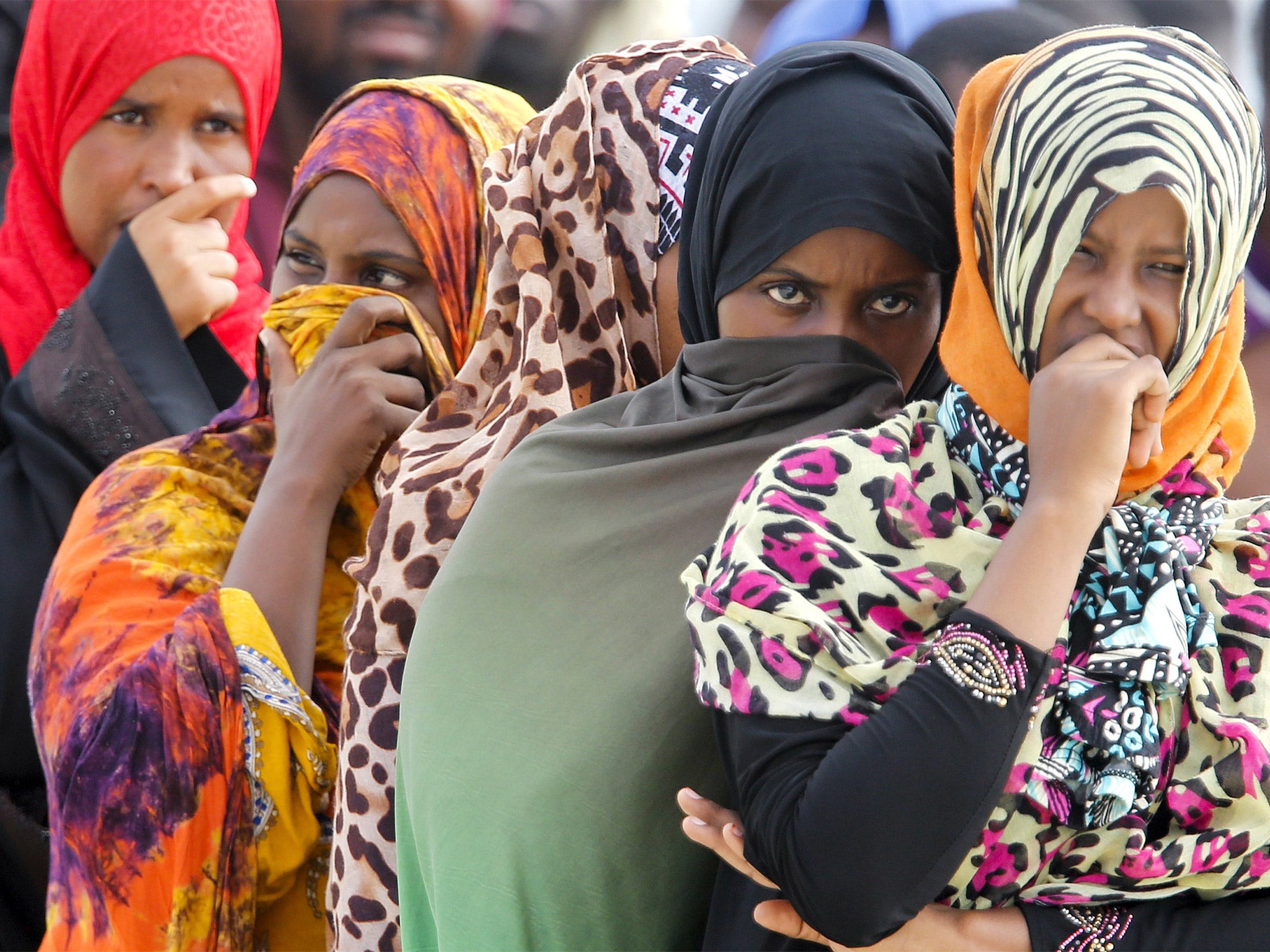 Migrants wait on the dock after disembarking from a Medecins Sans Frontieres ship carrying 320 migrants in the Sicilian harbour of Augusta, on Tuesday