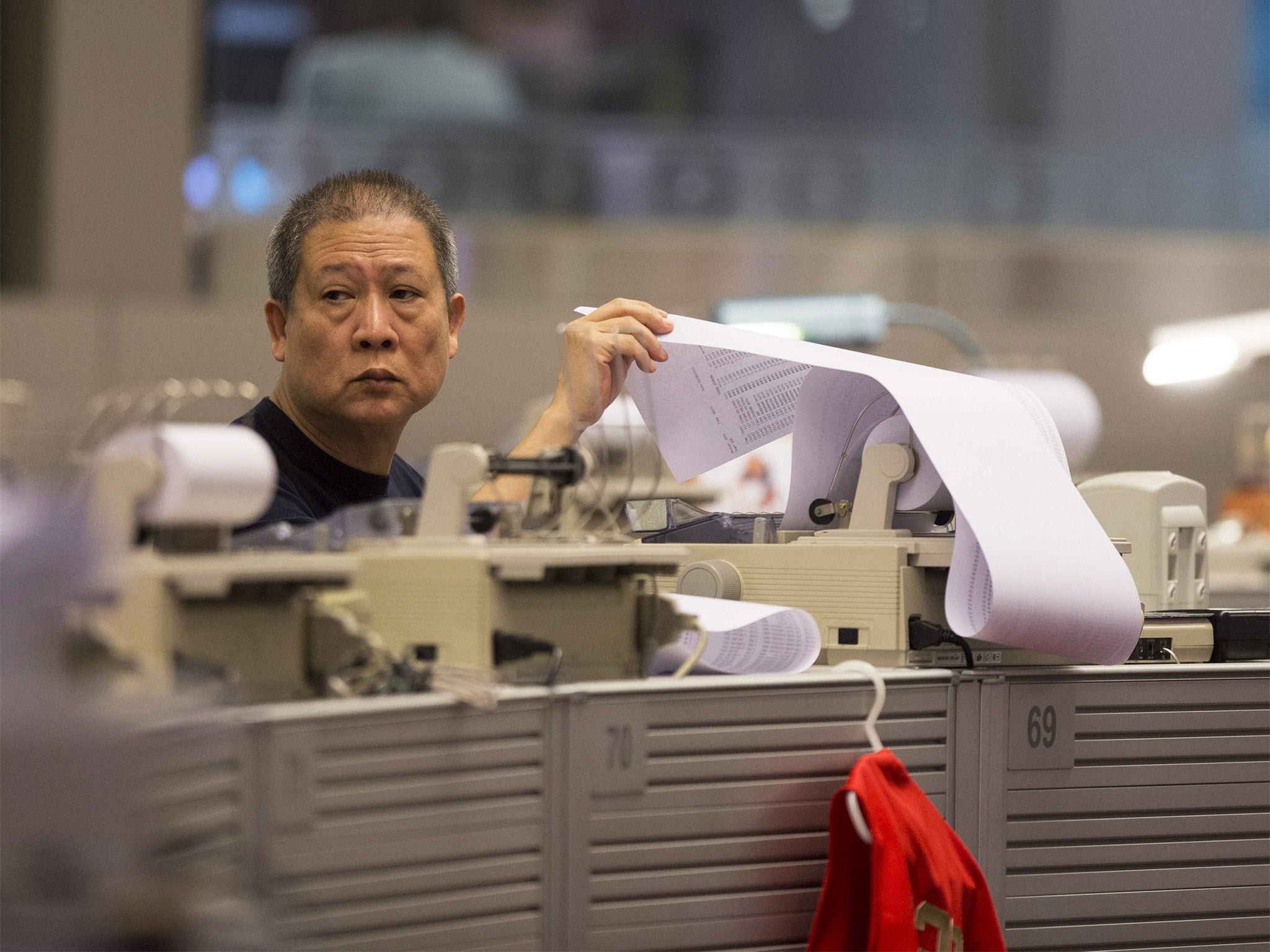 A stock broker prints a list of the day's transactions in Hong Kong