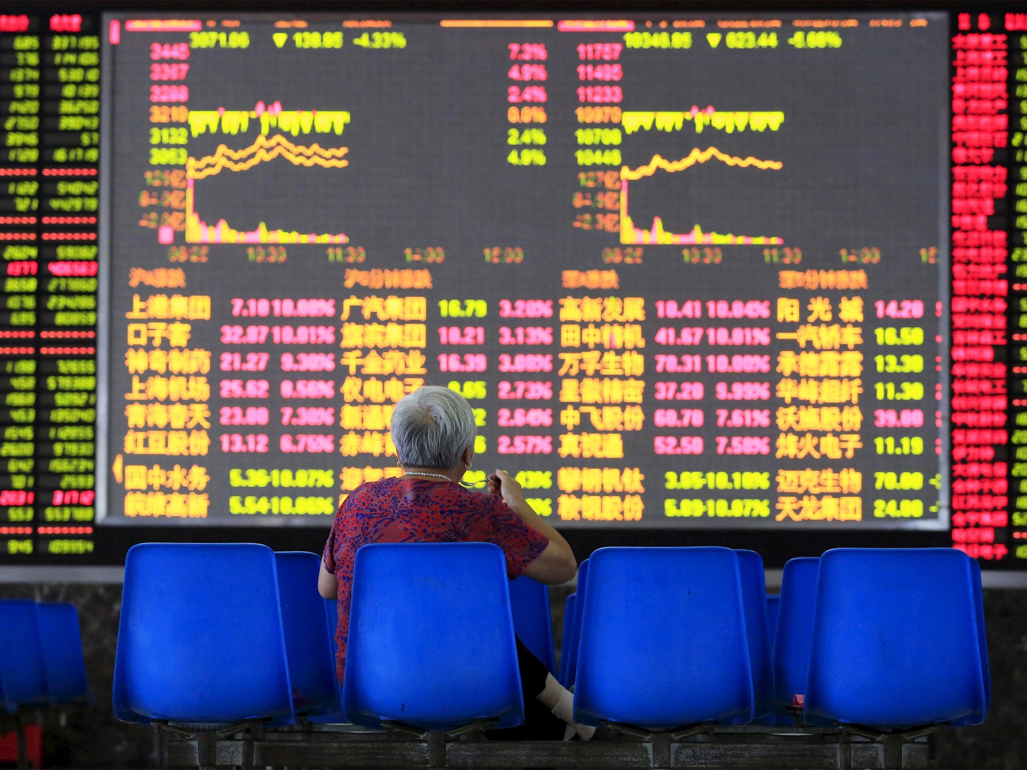 An investor looks at an electronic board showing stock information at a brokerage house in Shanghai