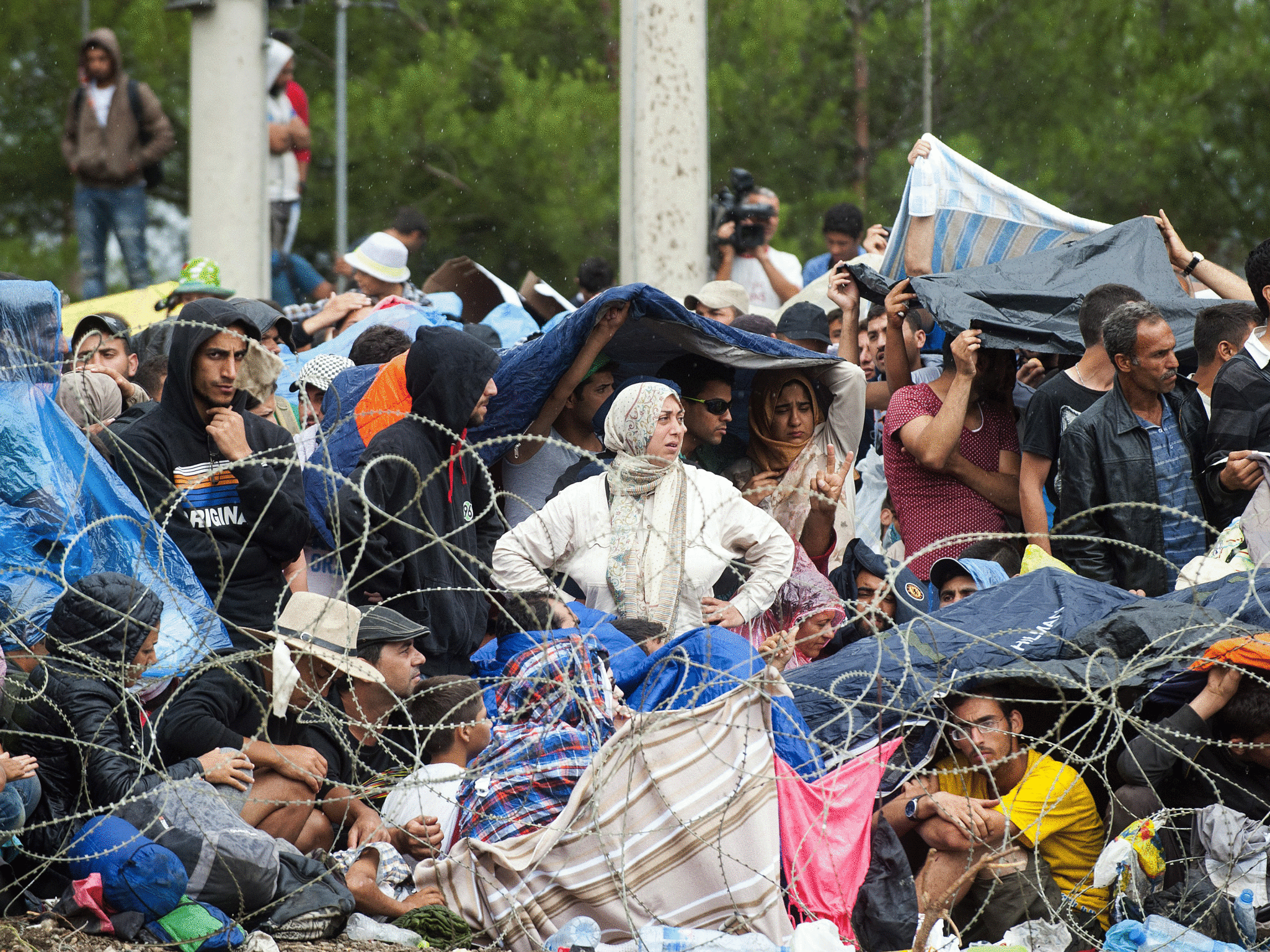 Refugees and migrants shelter from the rain along the Macedonian-Greek border