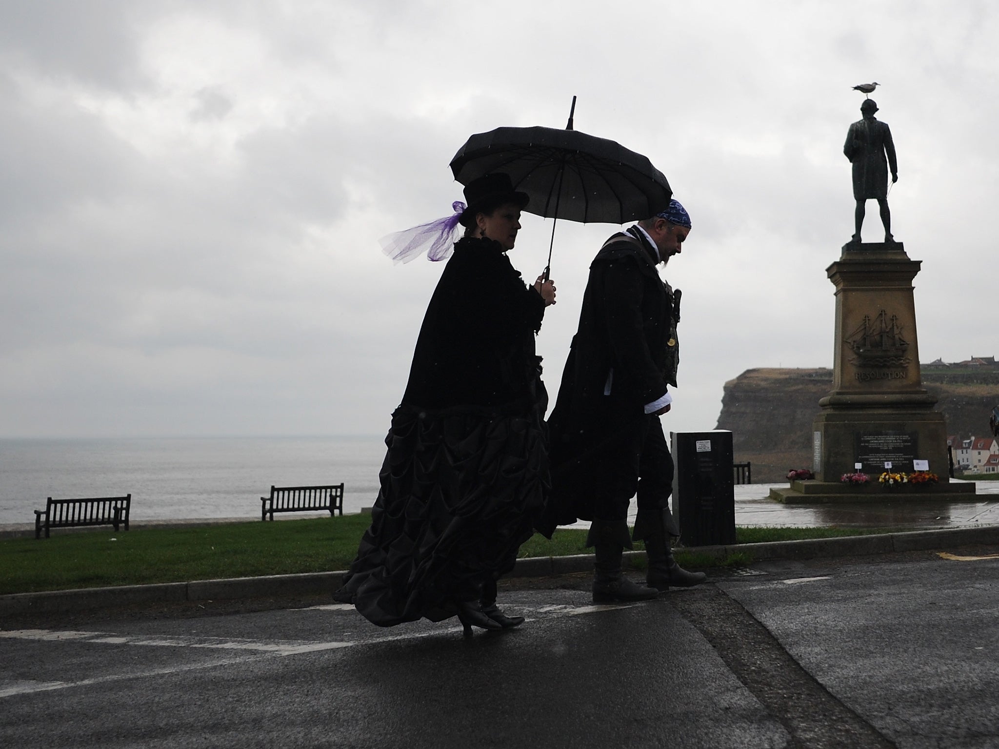 Two goths walk in the rain as they visit the Goth weekend in Whitby, England