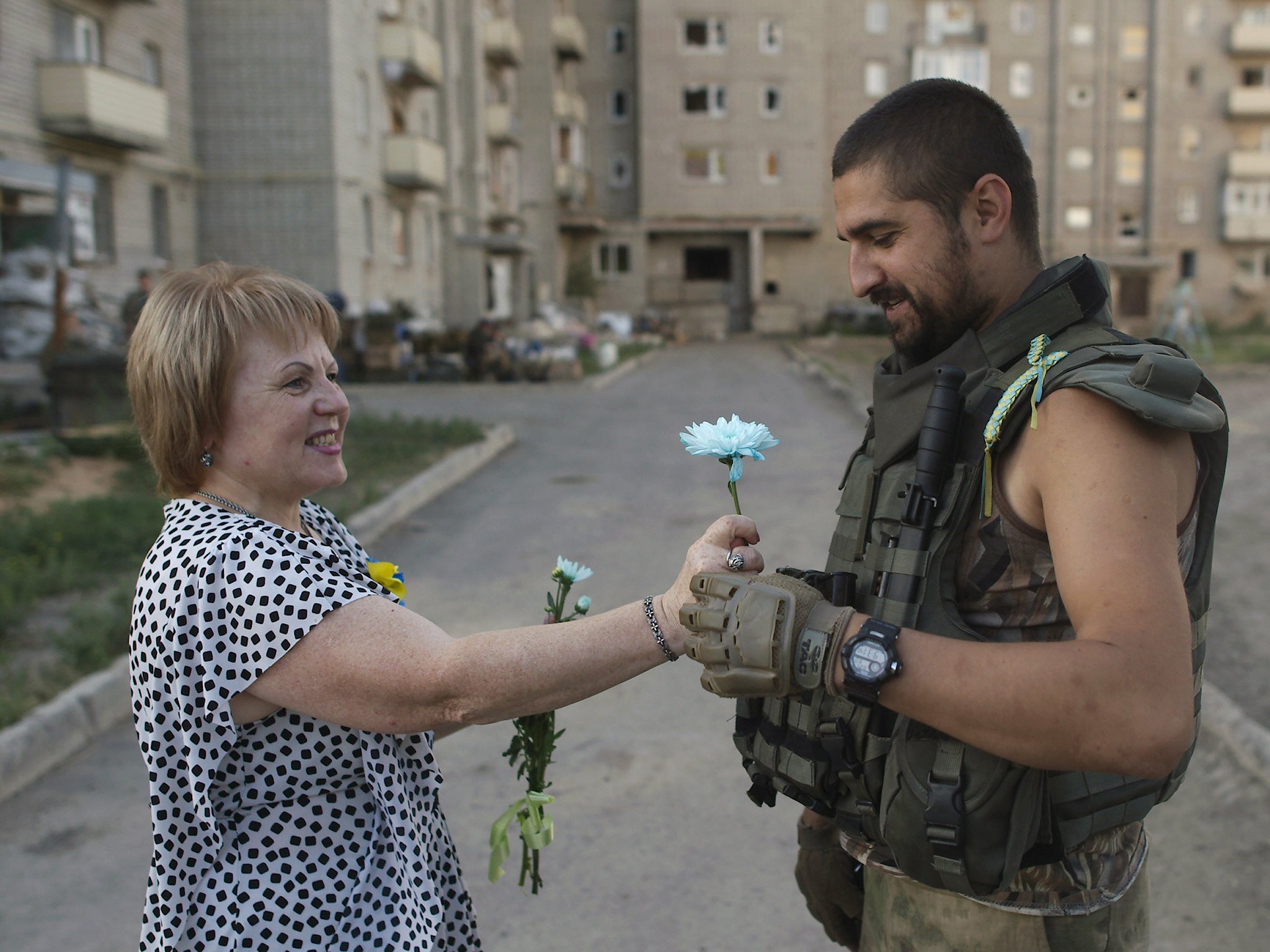 A woman gives a flower to a Ukrainian serviceman during the Independence Day celebrations in Avdiivka, Donetsk region