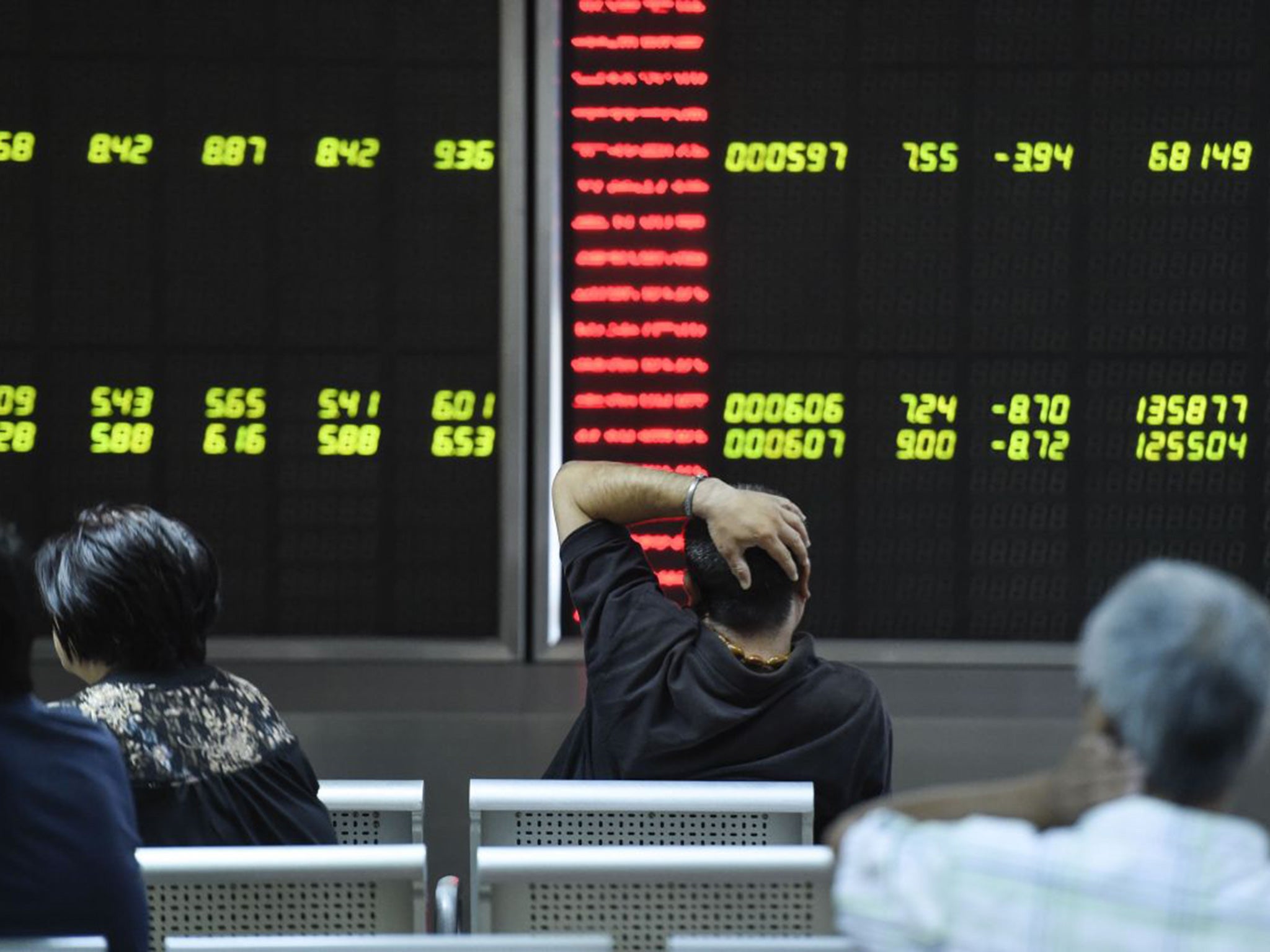 Investors look at screens showing stock market movements at a securities company in Beijing on August 25, 2015