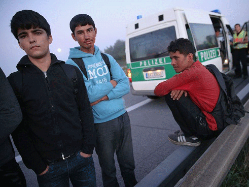 Police prepare to load a group of Afghan migrants into a van after the migrants crossed from Austria into Germany