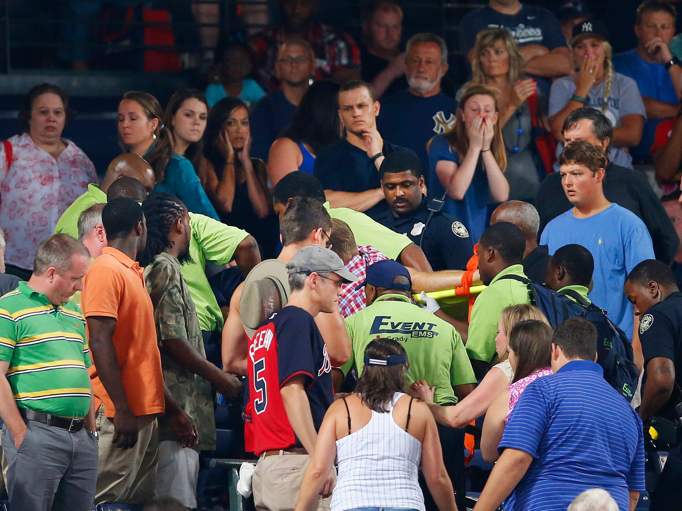 Rescue workers carry the fan from the stands at Turner Field during a baseball game