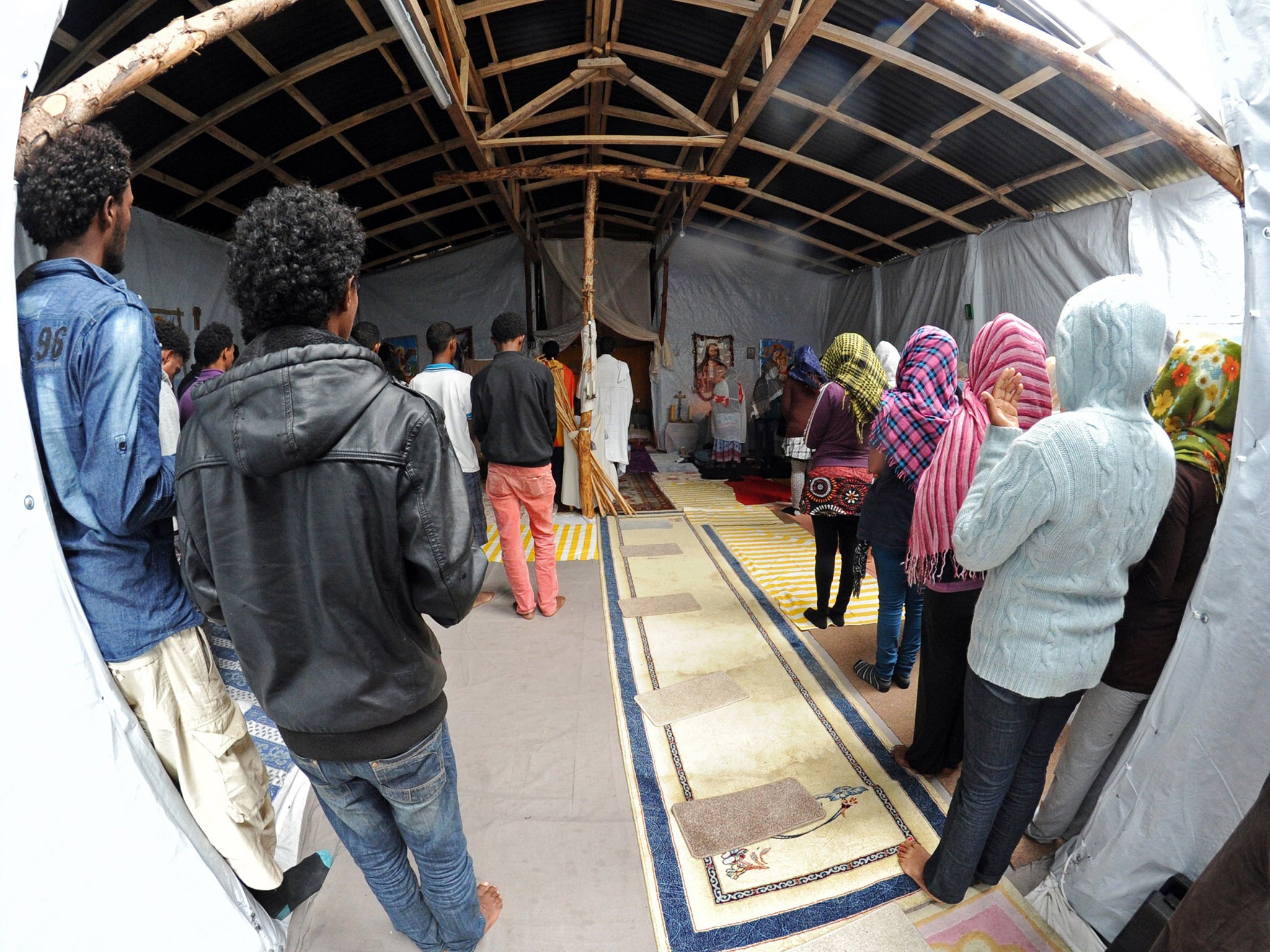 Migrants attend a mass in a makeshift church built in the migrant camp in Calais