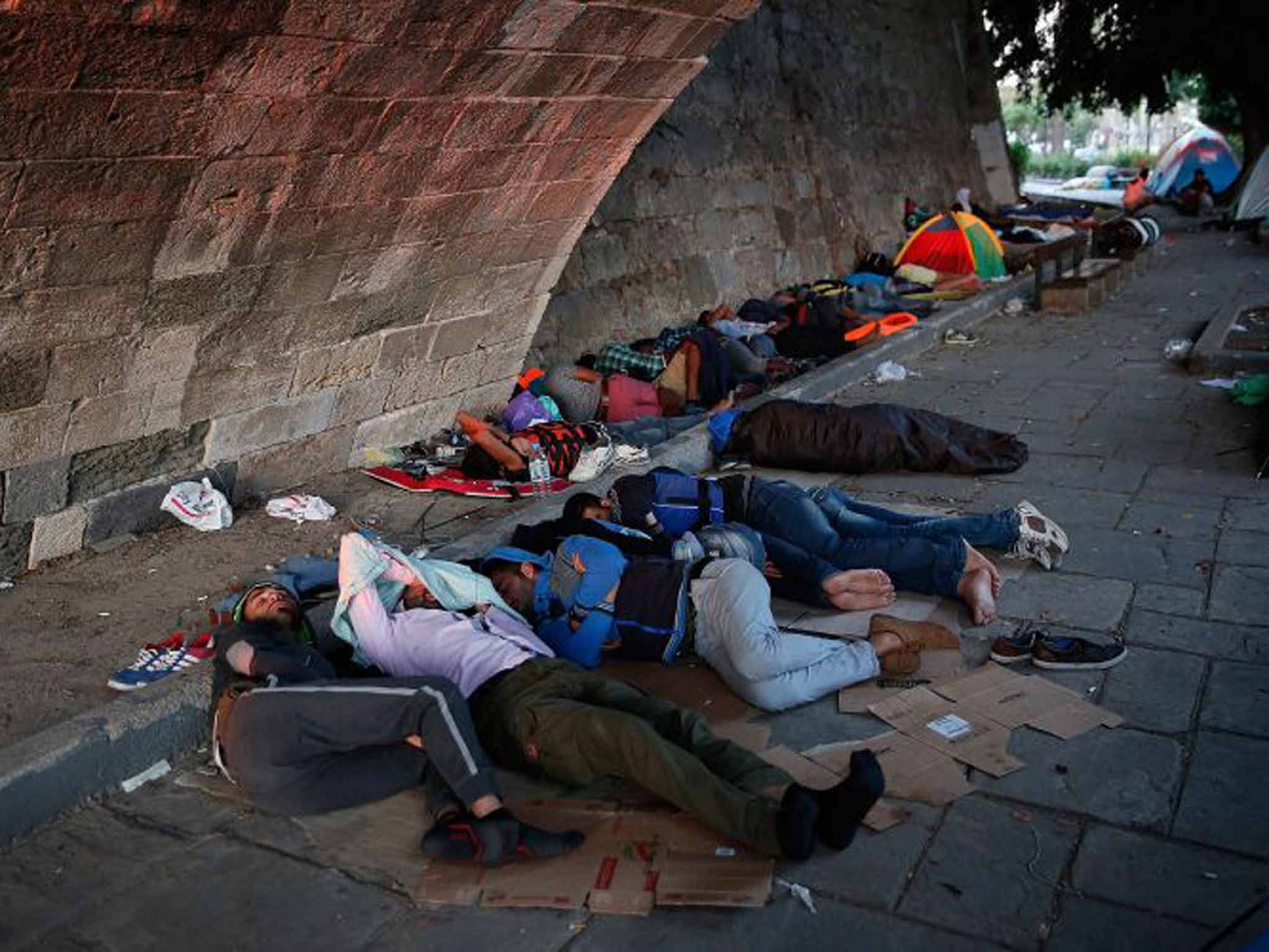 Refugees sleep rough under a bridge