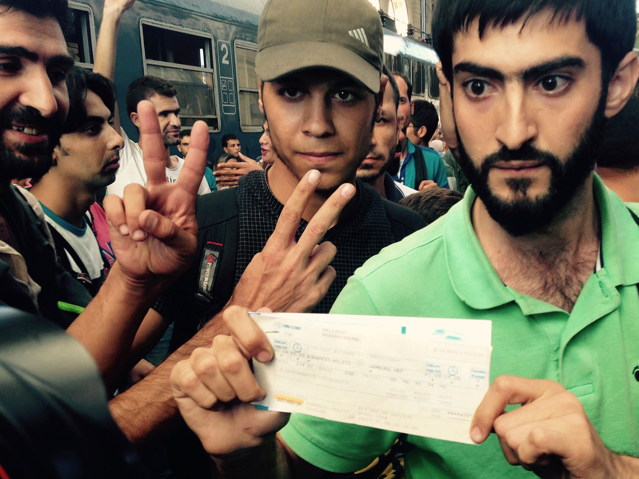 Syrian migrants show their train tickets to Germany and demand being let on the train but Keleti train terminal