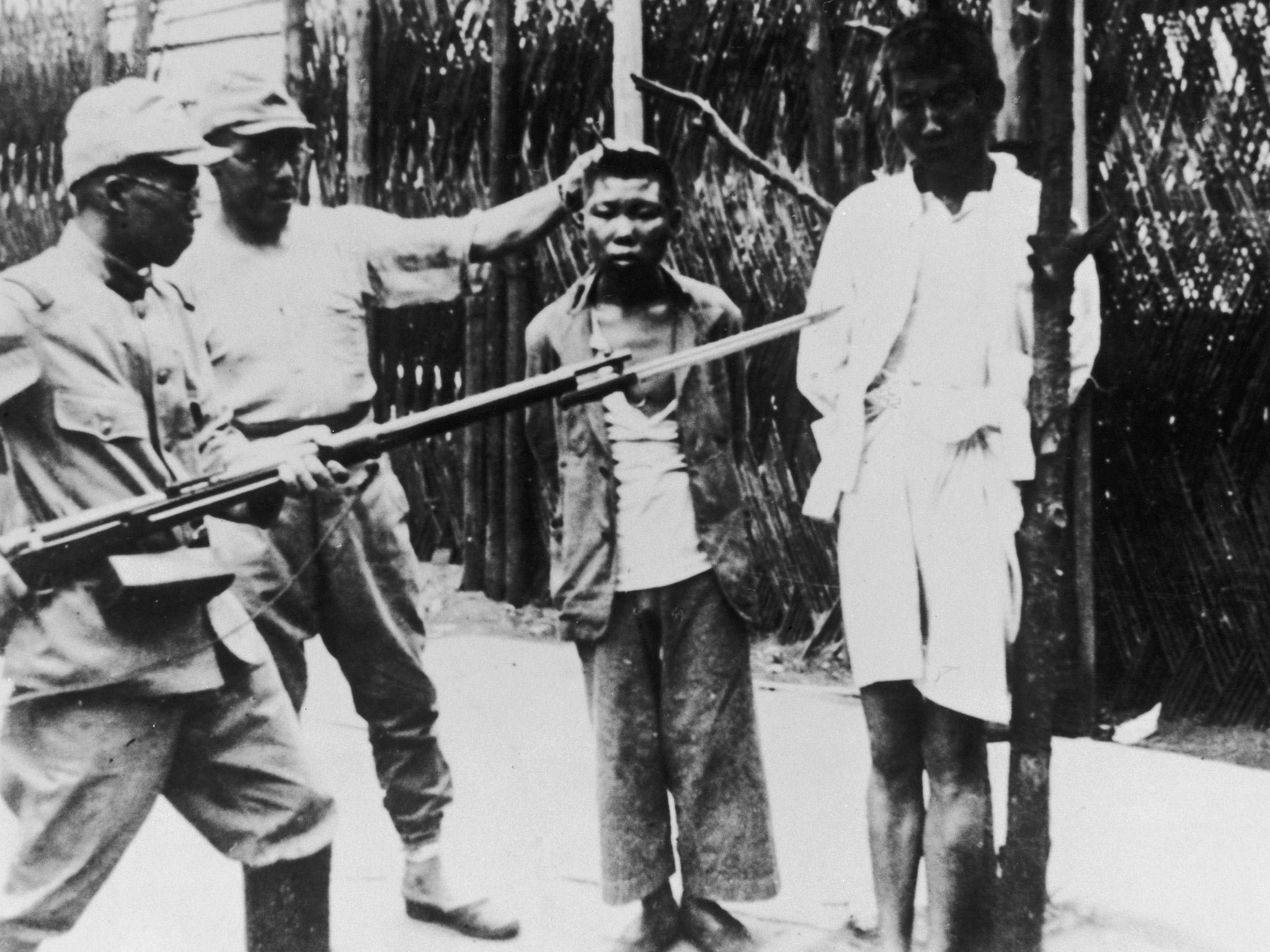 Japanese soldiers taunt a pair of young Chinese prisoners during the Second Sino-Japanese War, 22nd August 1938 (Getty)