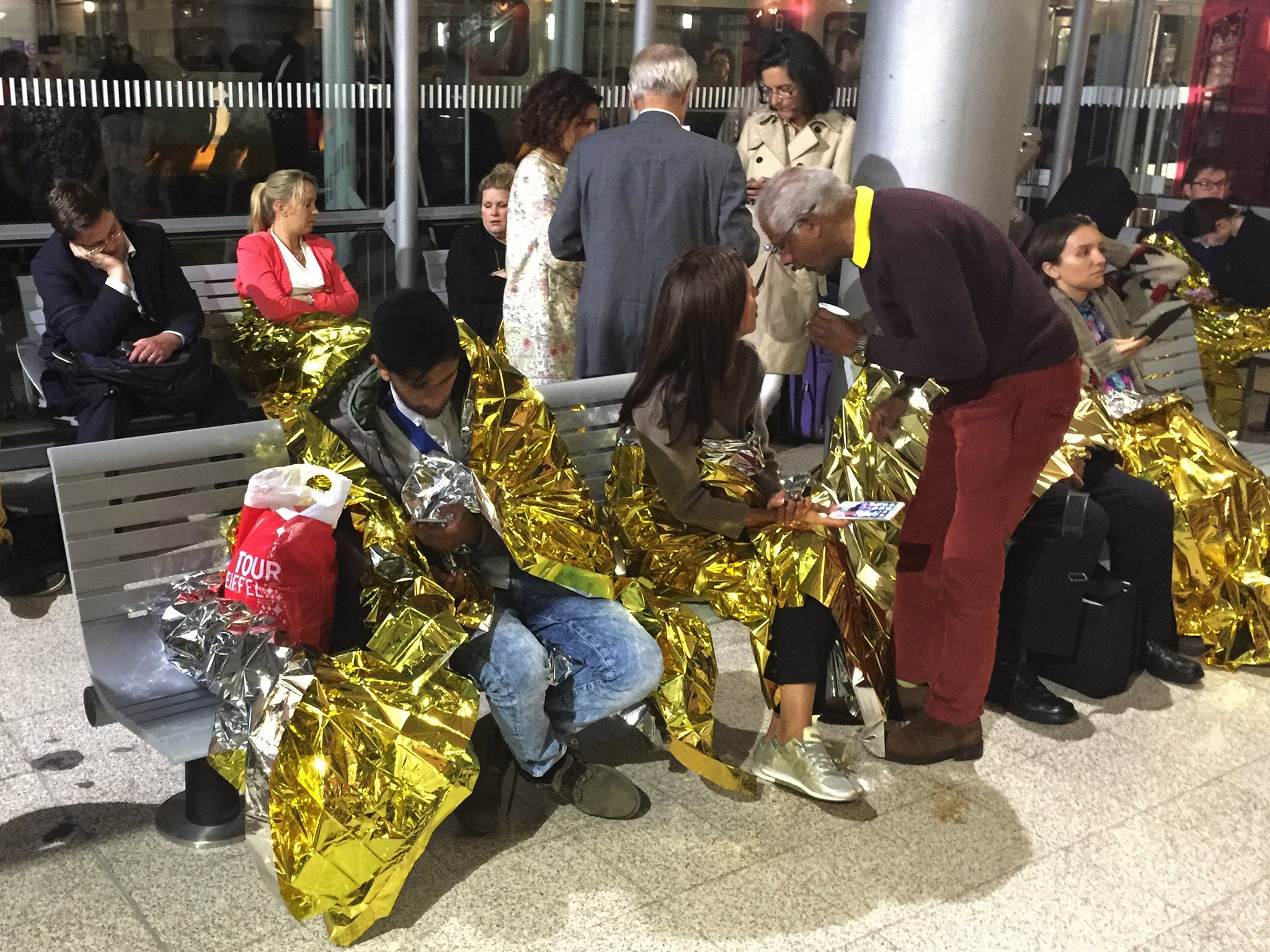 Passengers wrapped in thermal foil blankets given out by emergency services after their Eurostar train was stranded at Calais Station