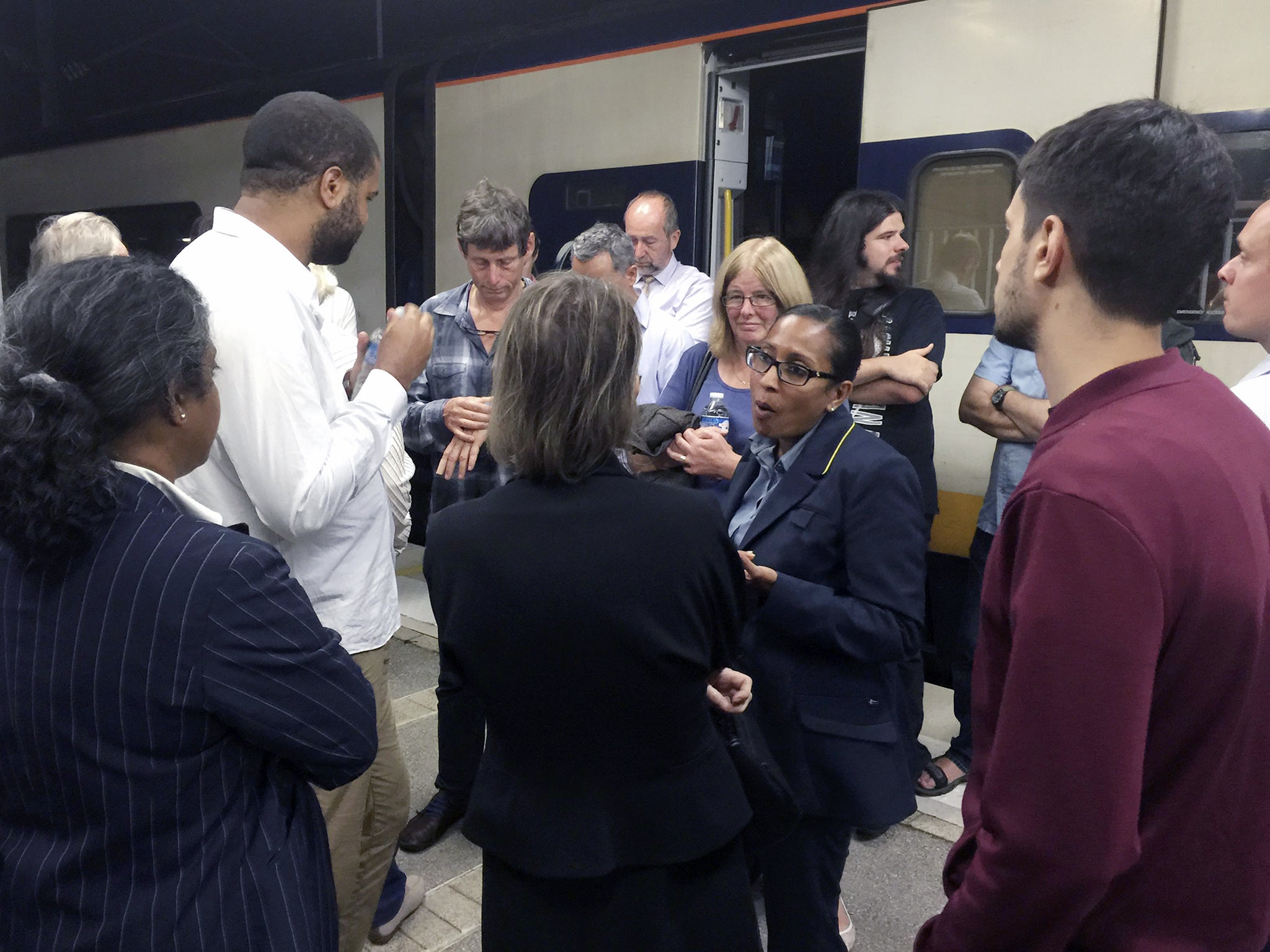 A Eurostar staff member (C) talks to passengers on a stranded Eurostar service at Calais Station